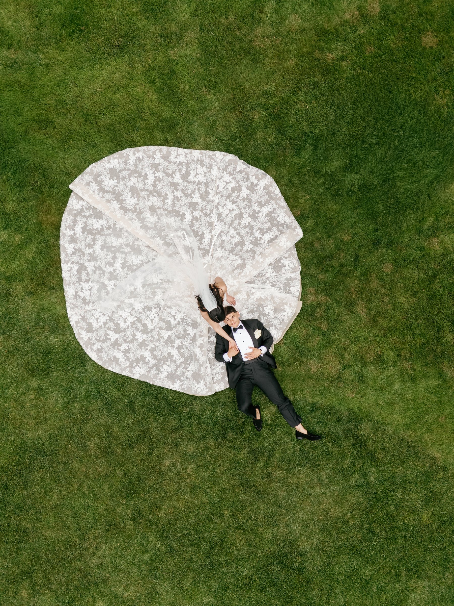 Kayla and Avery lying in the middle of her gown, spread in a circle on the lawn, seen from above at Smith Farm Gardens