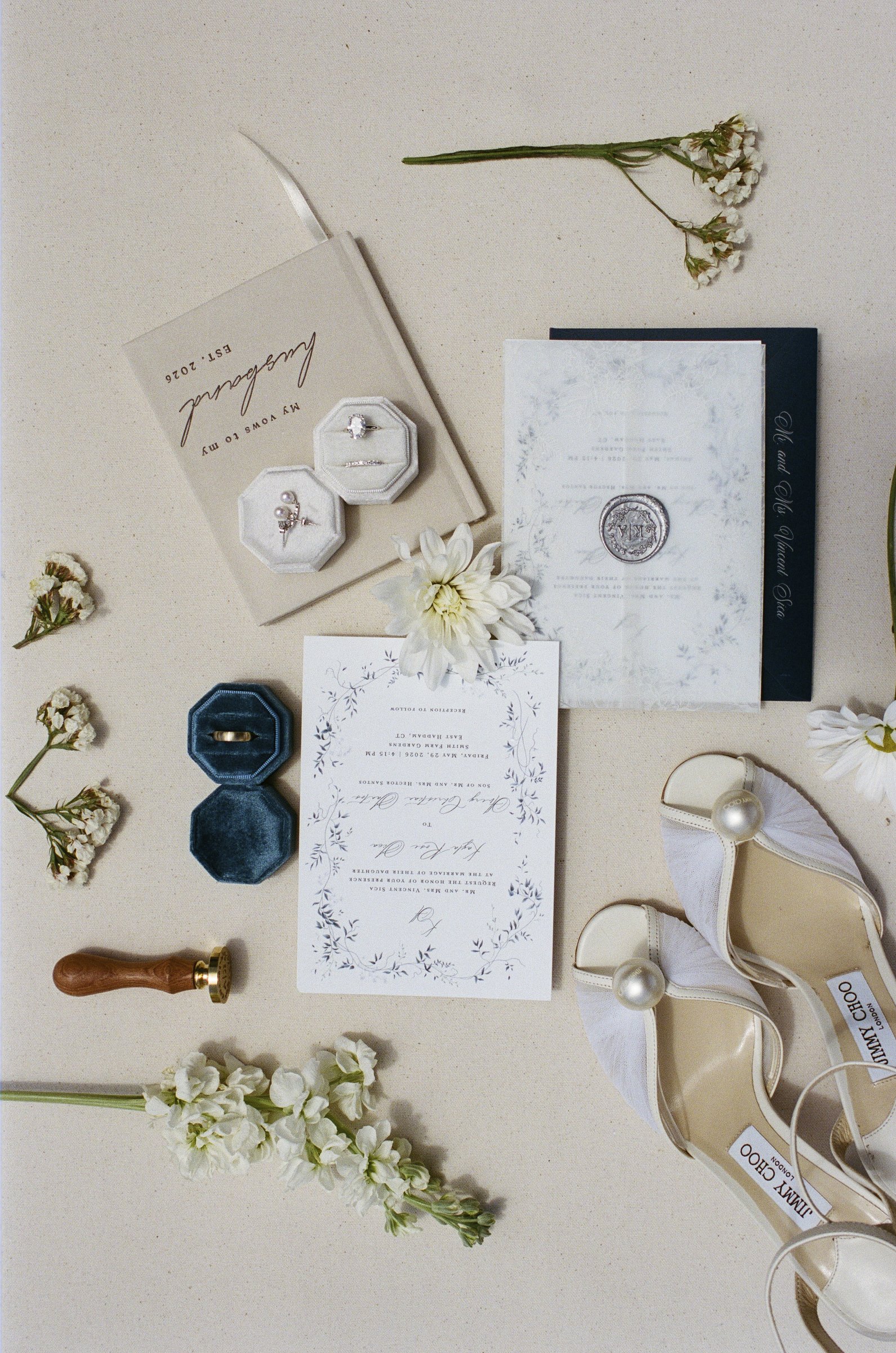 The invitation suite, rings and a sprig of flowers laid out before the day
