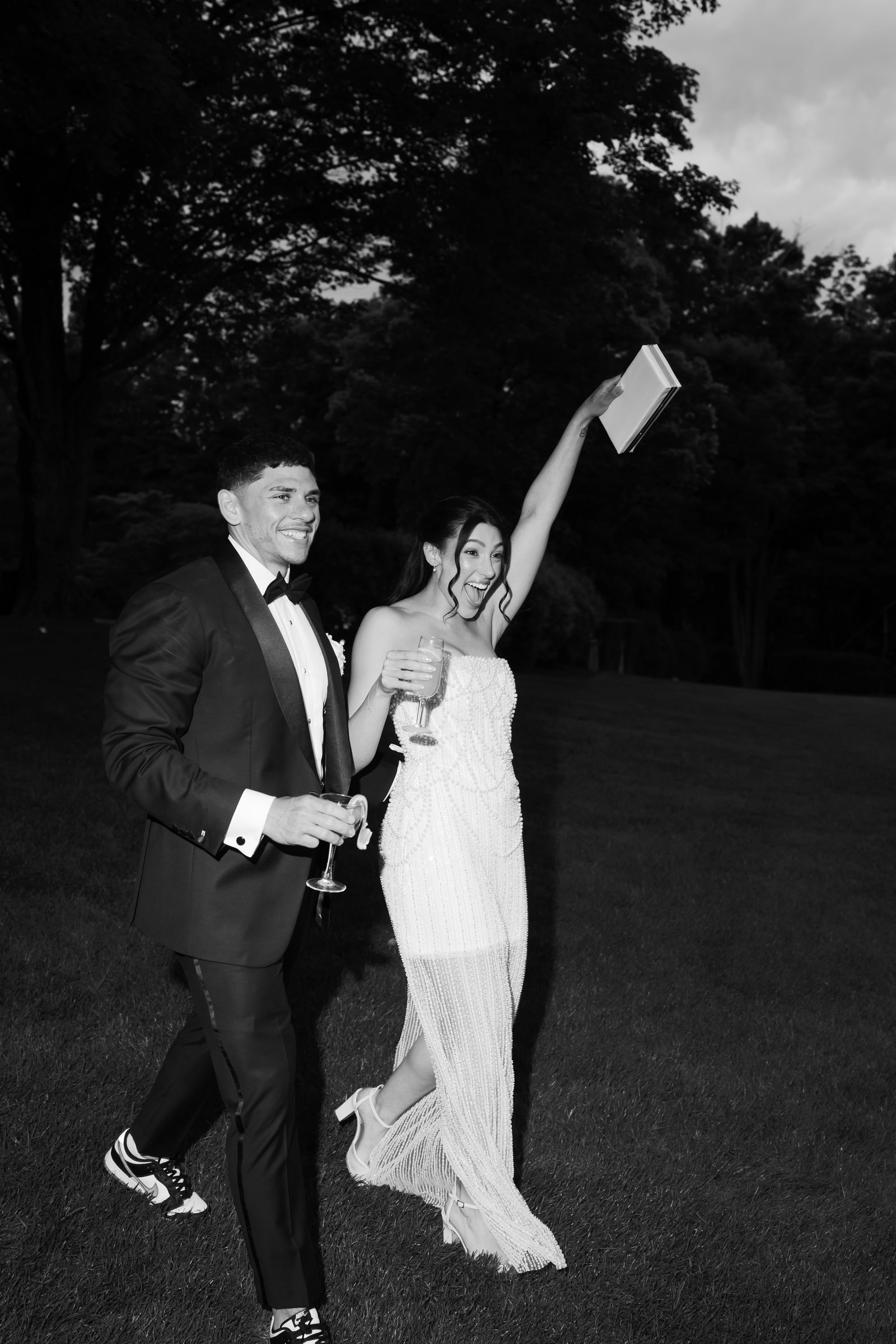 Kayla throwing her arm up and Avery laughing as they cross the lawn at night, in black and white