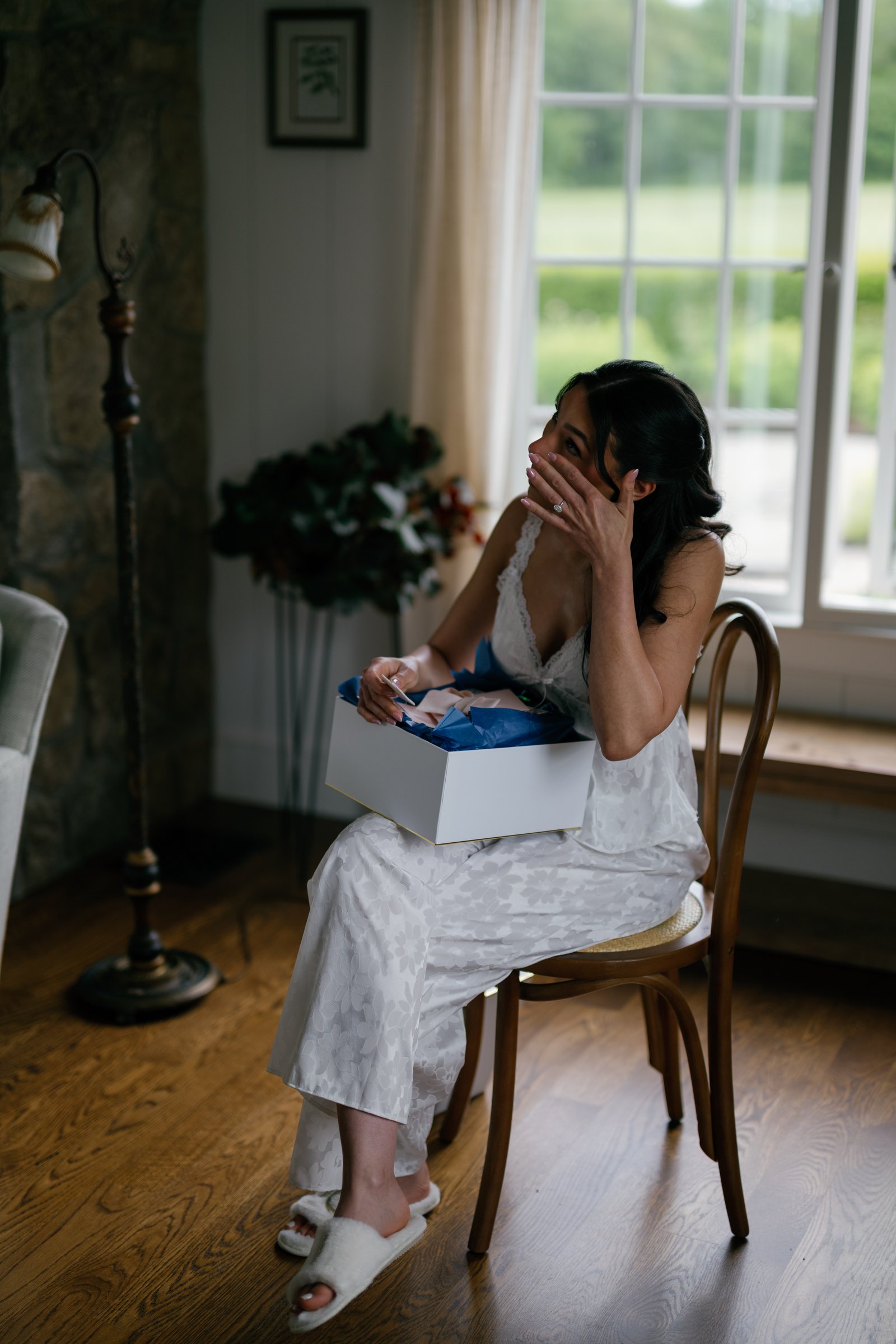 Kayla reading a letter with her hand over her face, a gift box on her lap