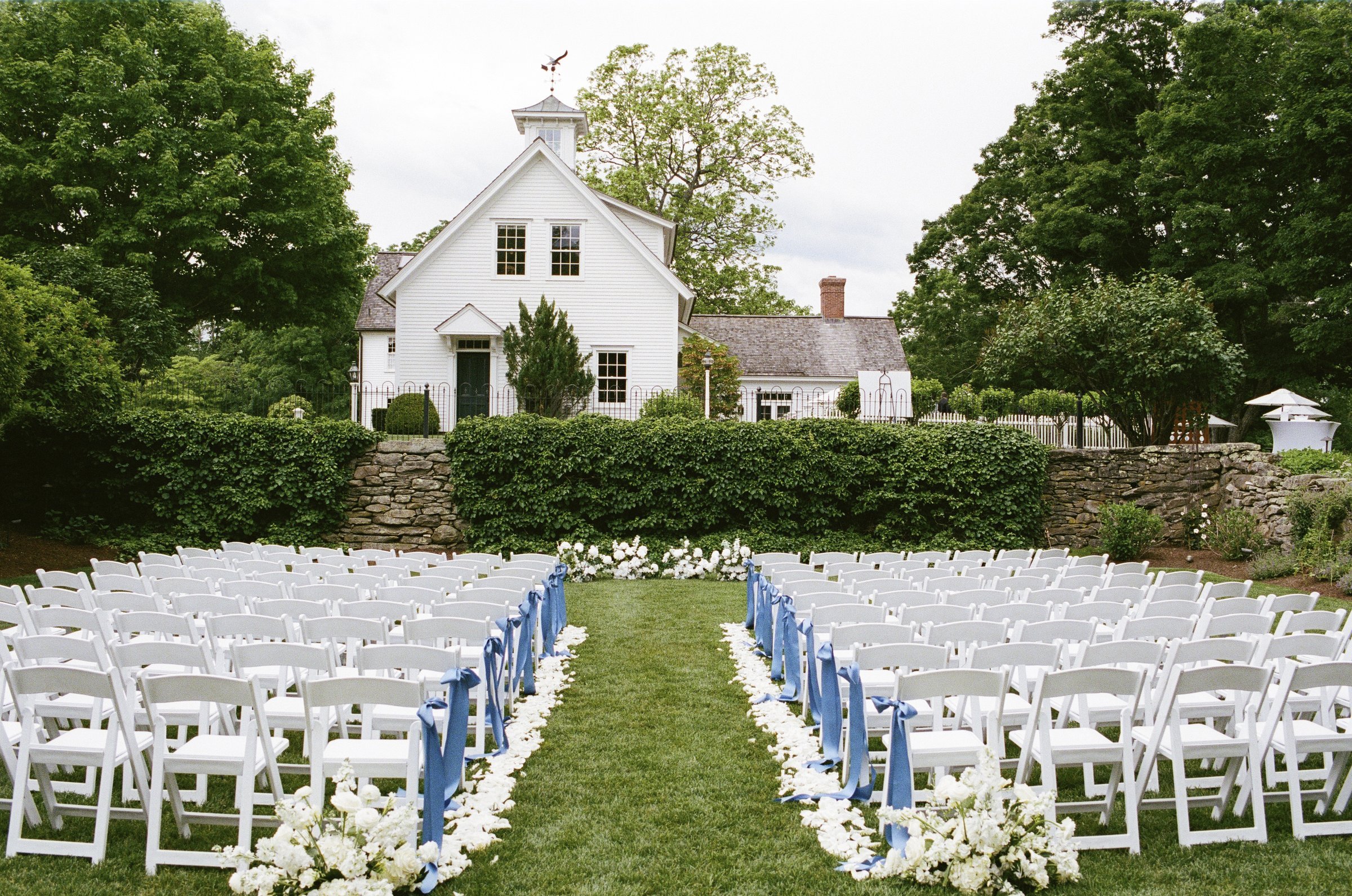 White ceremony chairs with blue ribbons and flowers before the guests arrive