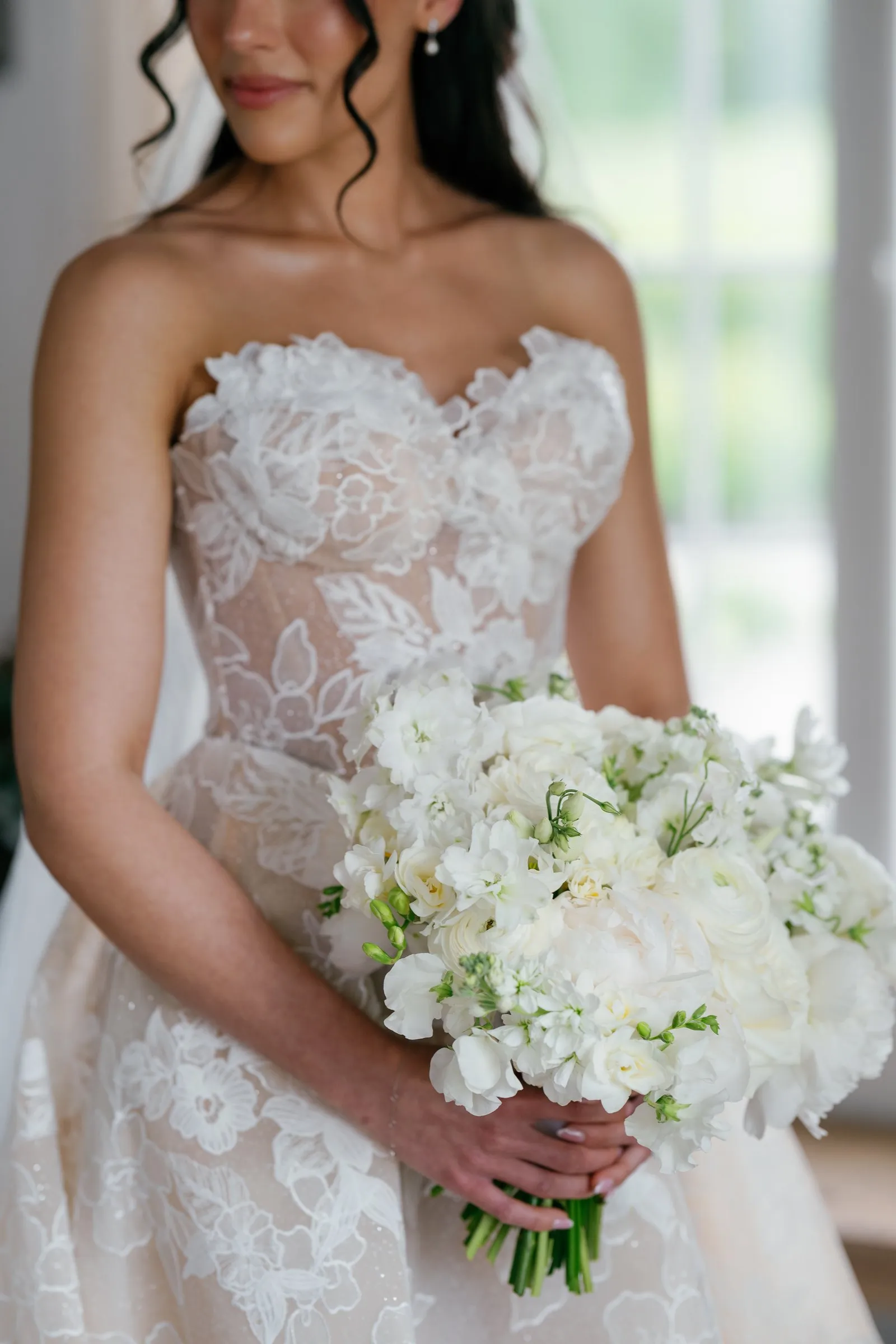 Kayla holding her bouquet of white flowers against her lace gown