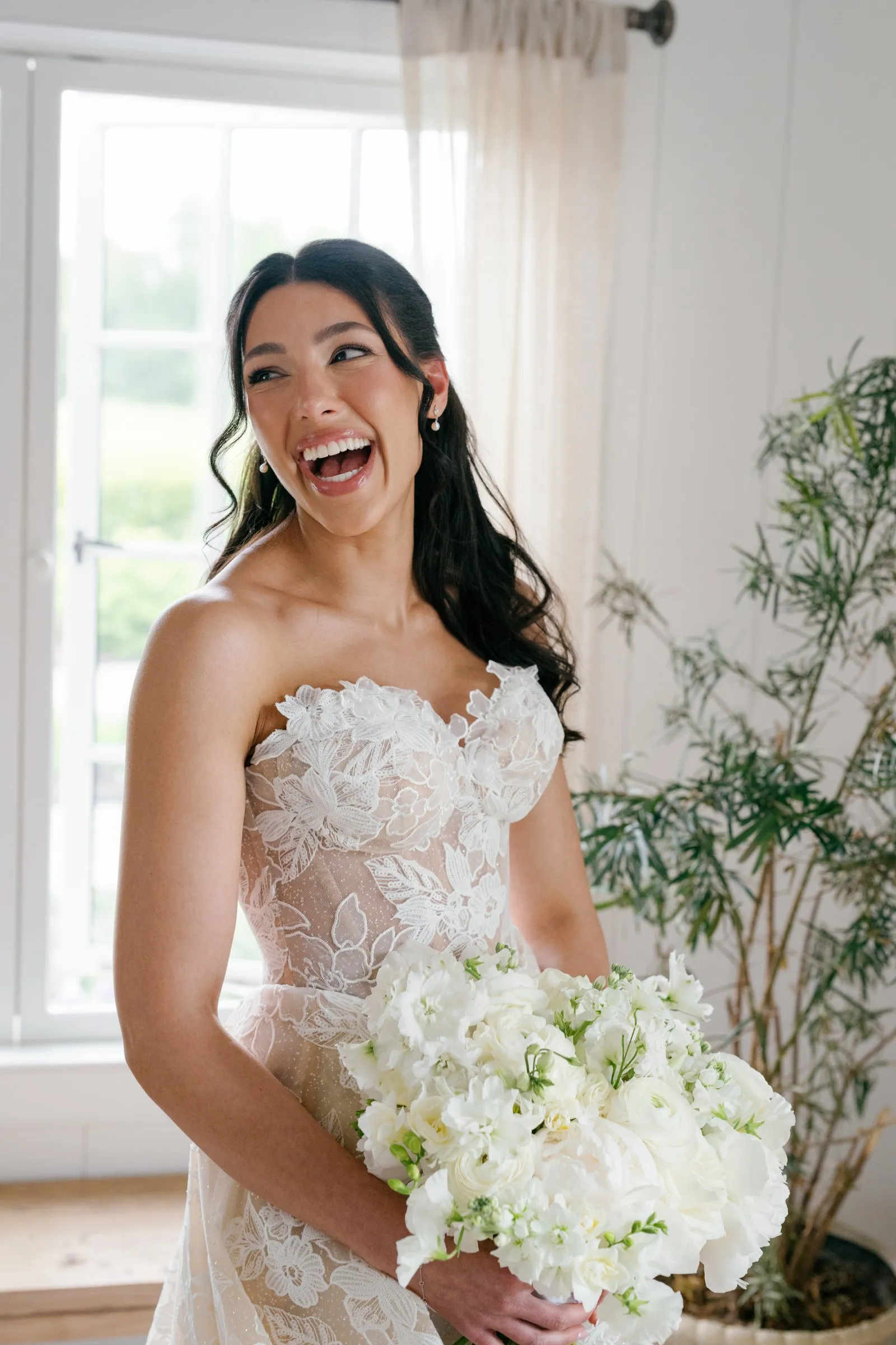 Kayla laughing with her bouquet in the bright cottage room