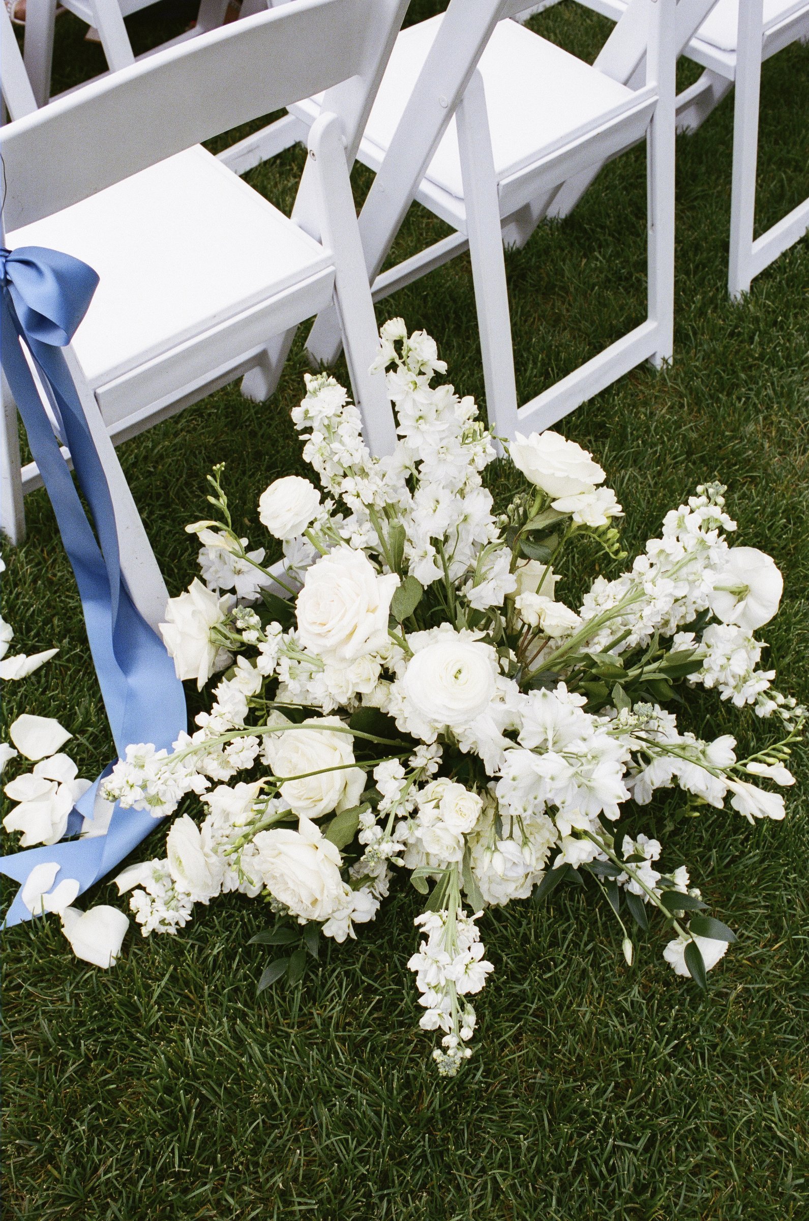 White flowers and a blue ribbon on the ceremony chairs