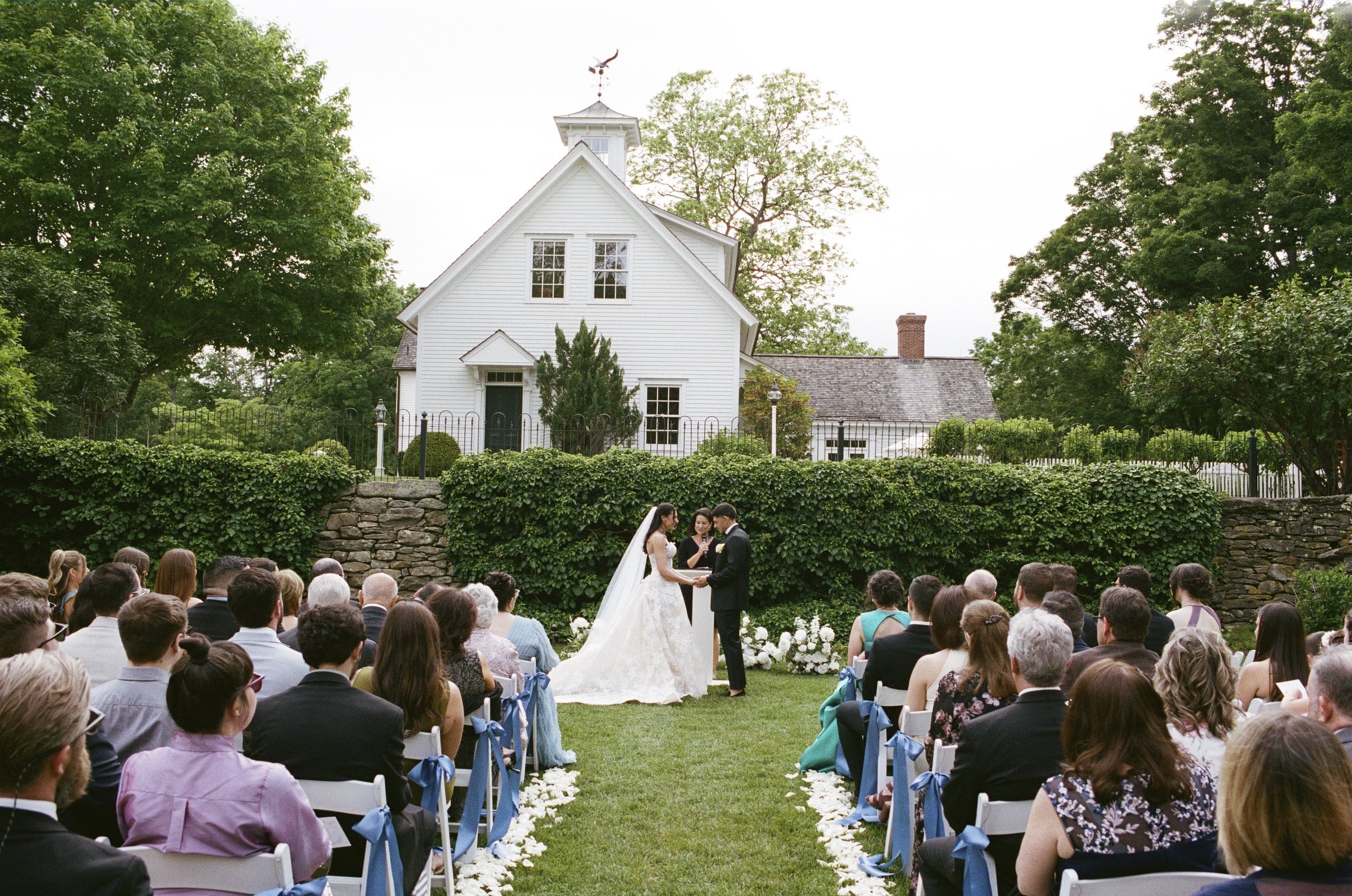 Guests seated for the ceremony in front of the farmhouse