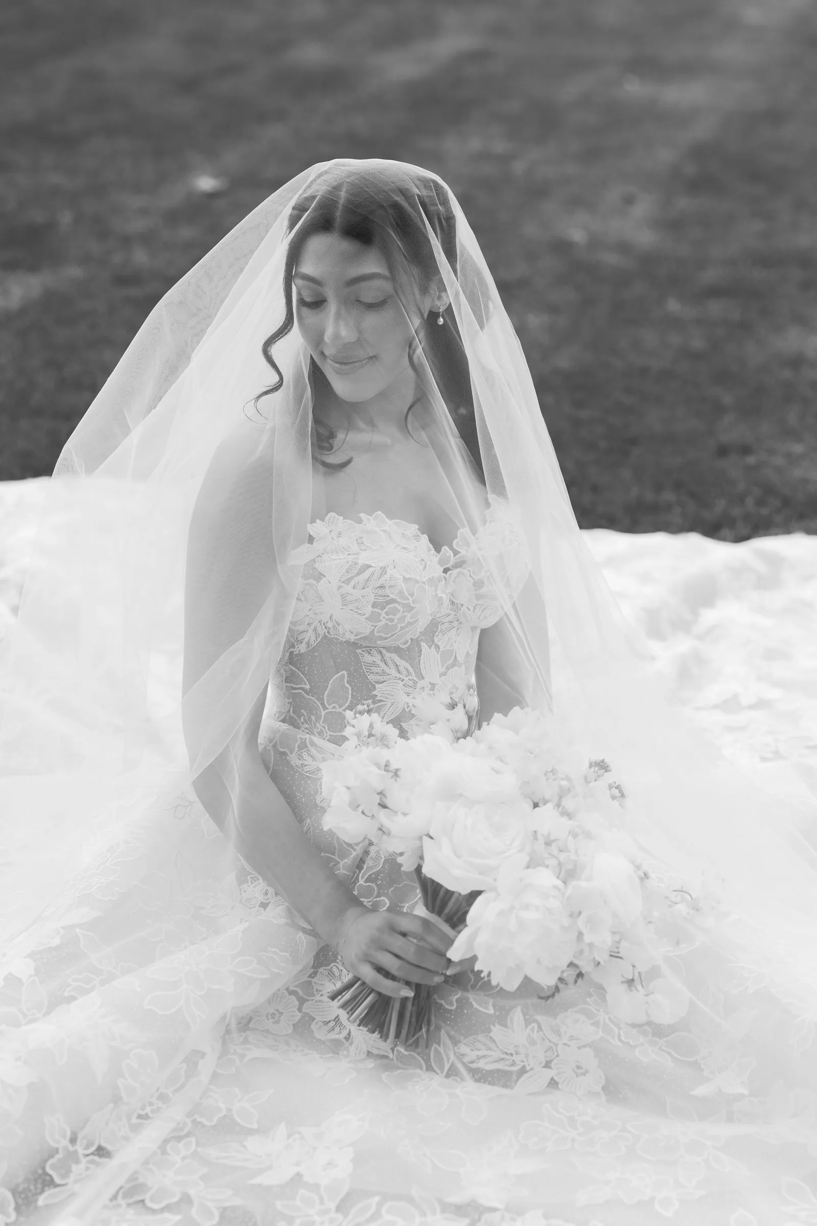 Kayla under her veil holding her bouquet, in black and white
