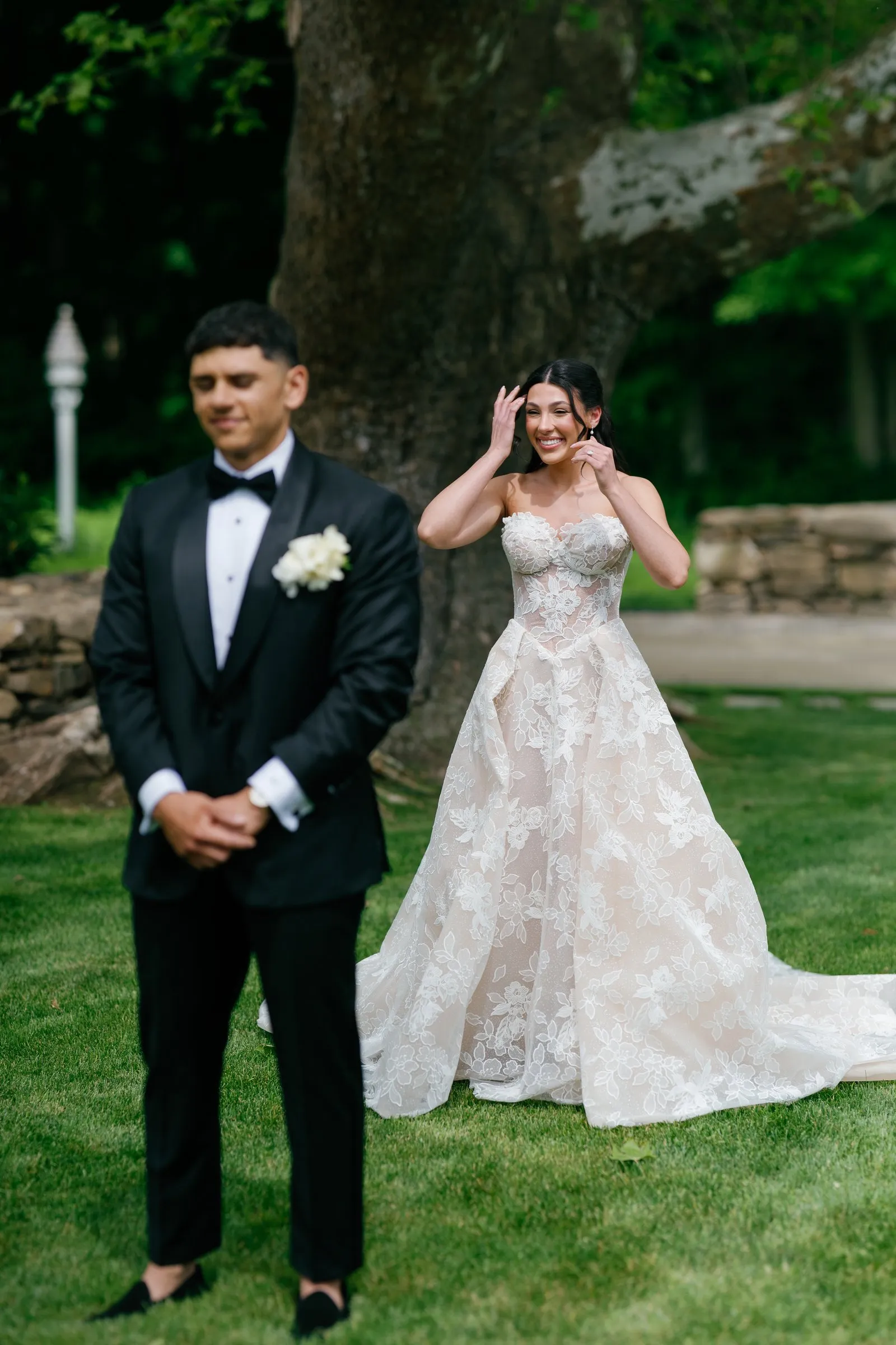 Avery waiting for the first look as Kayla giggles behind him under the sycamore