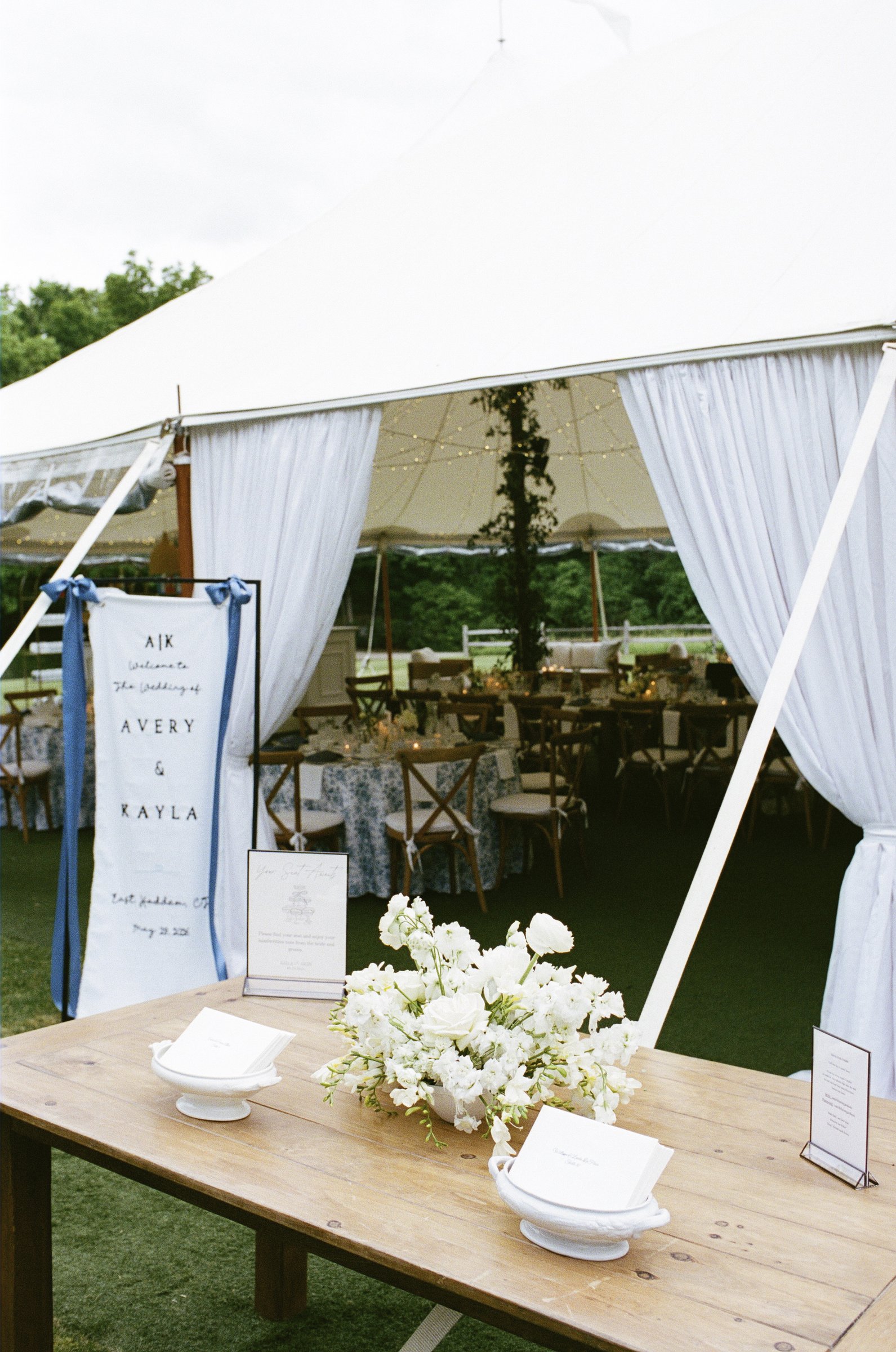The tent entrance with white flowers and the seating sign
