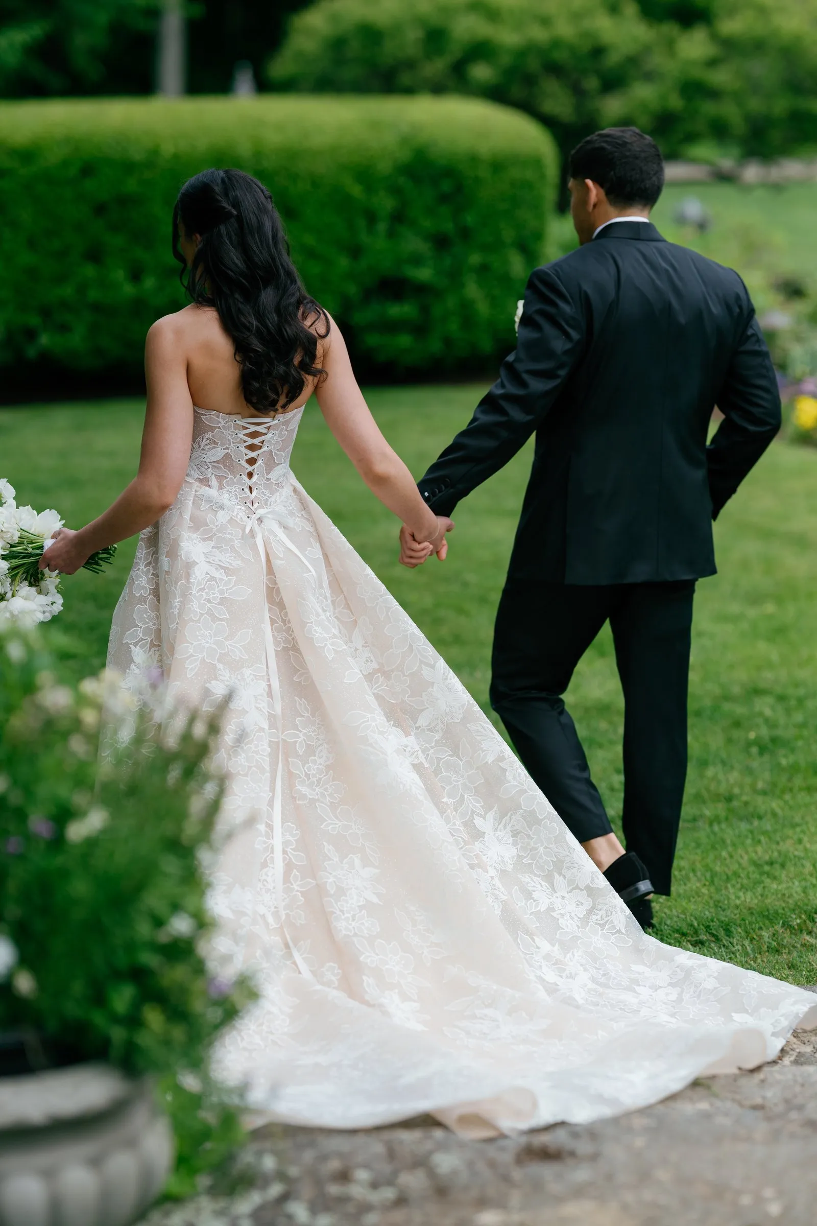 Kayla and Avery walking hand in hand along the hedges