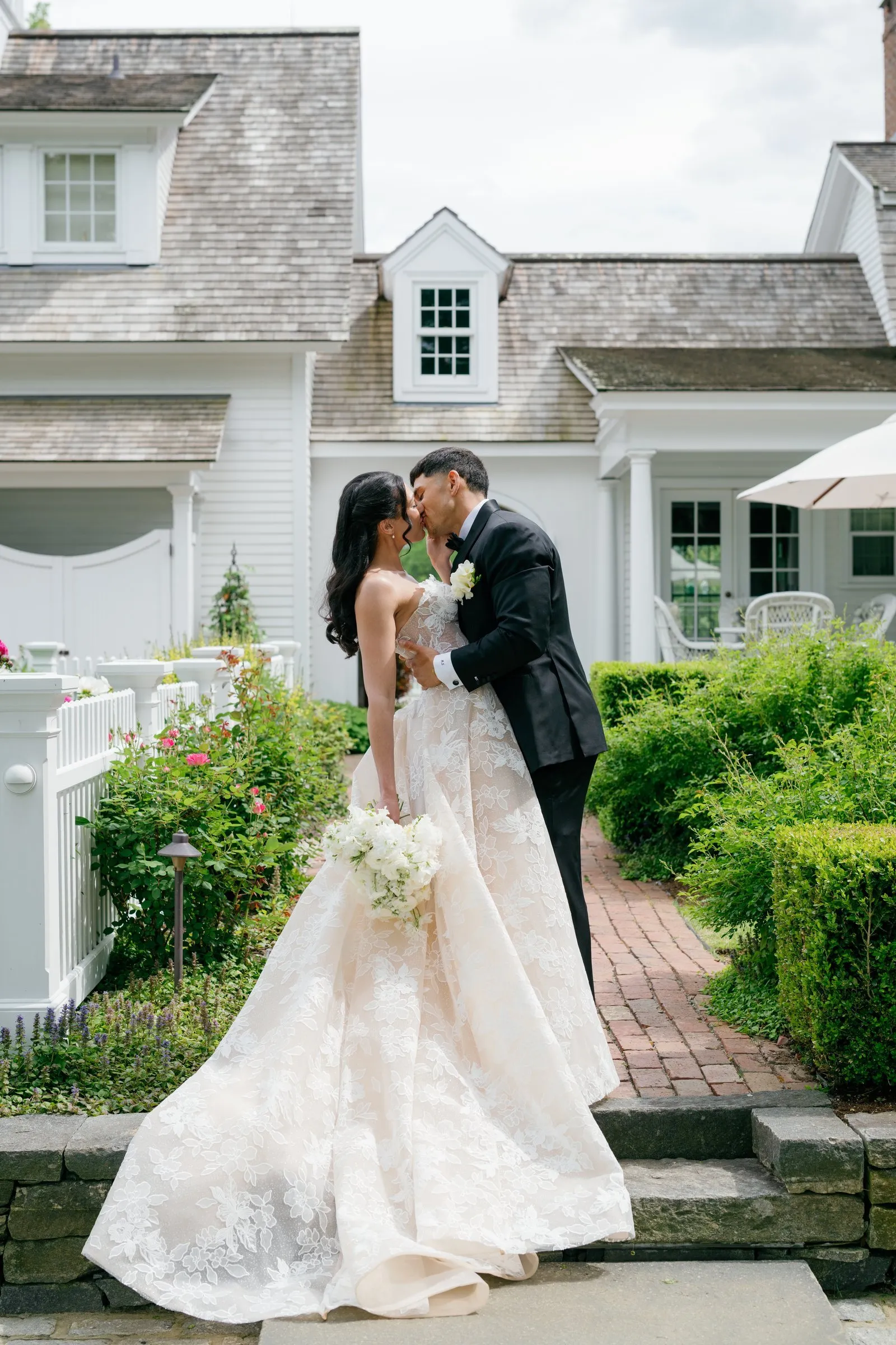 Kayla and Avery kissing on the brick path in front of the house
