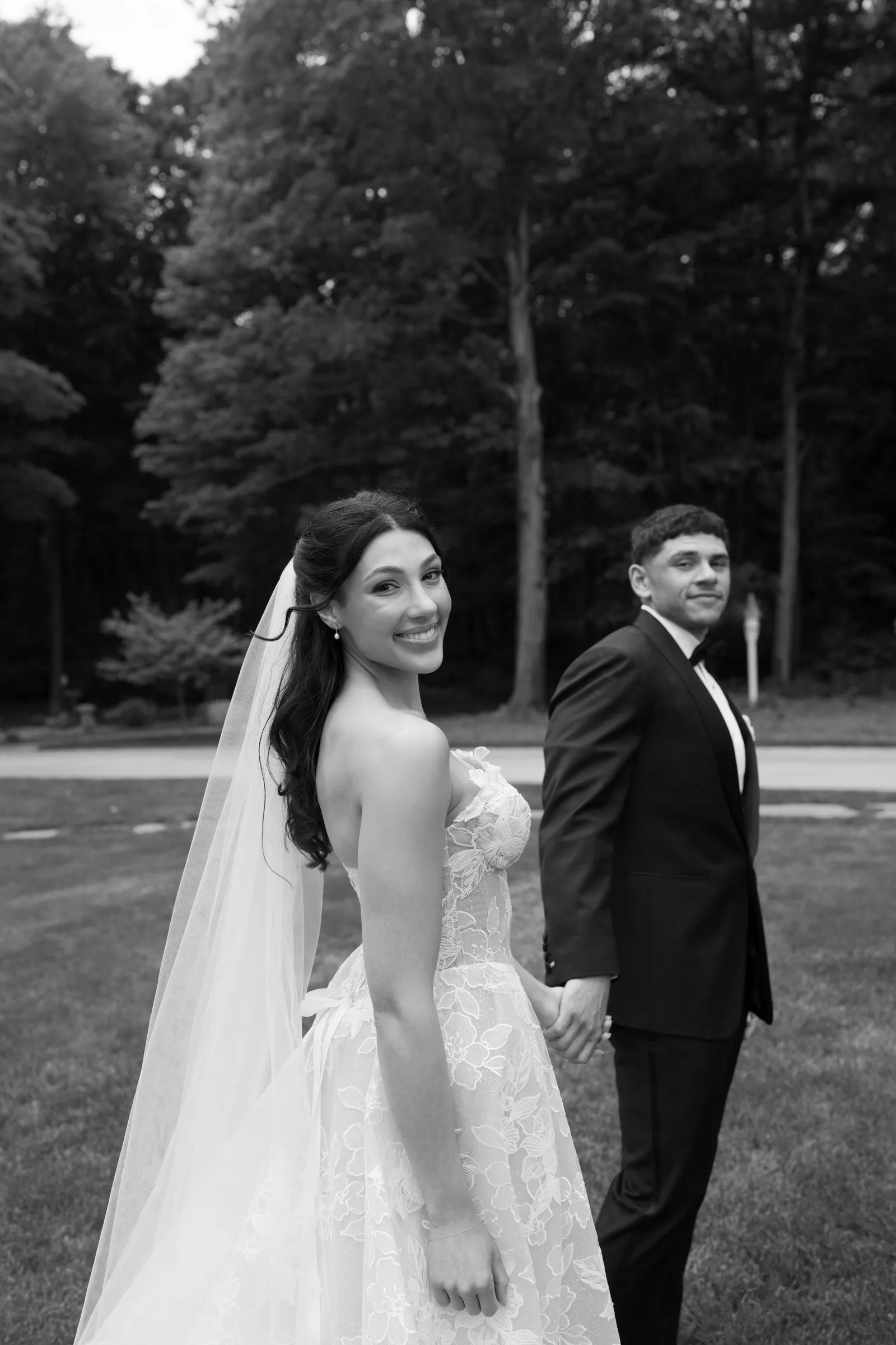 Kayla smiling back over her shoulder as she holds Avery's hand, in black and white