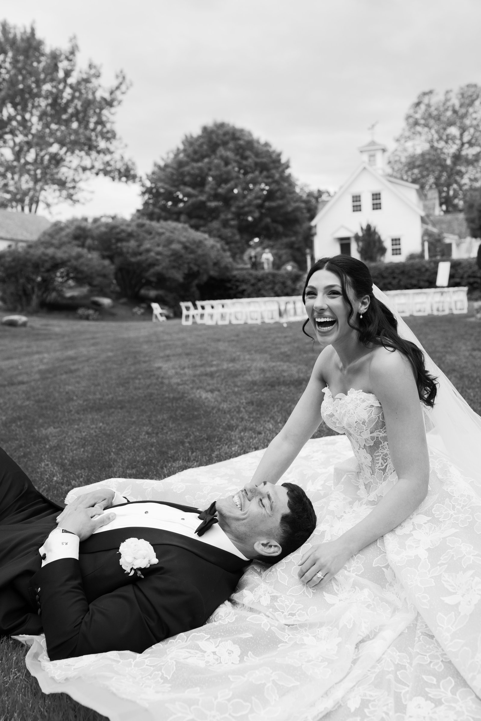 Kayla laughing as Avery lies with his head in her lap on the lawn, in black and white