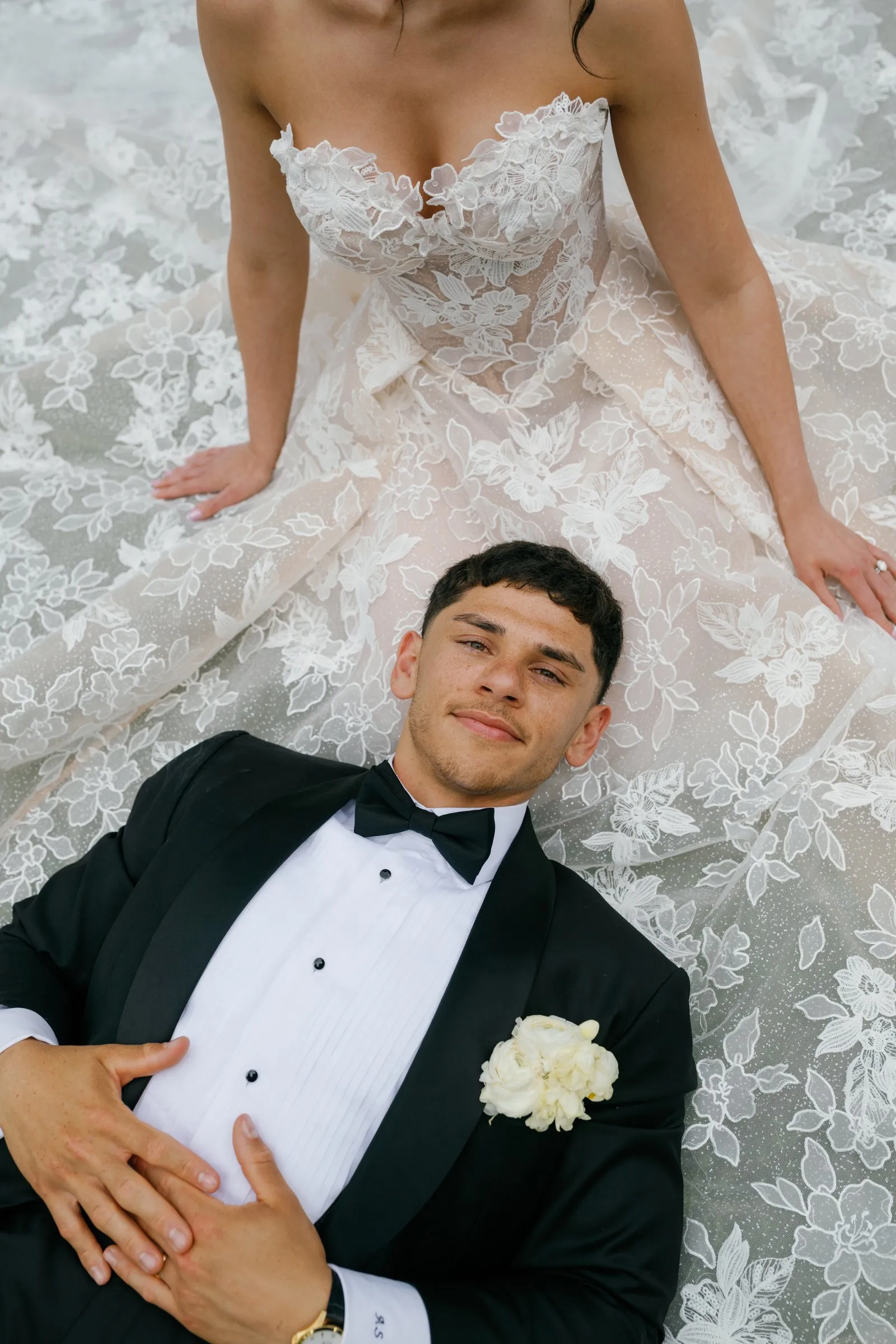 Avery lying on Kayla's lace gown, looking up at the camera