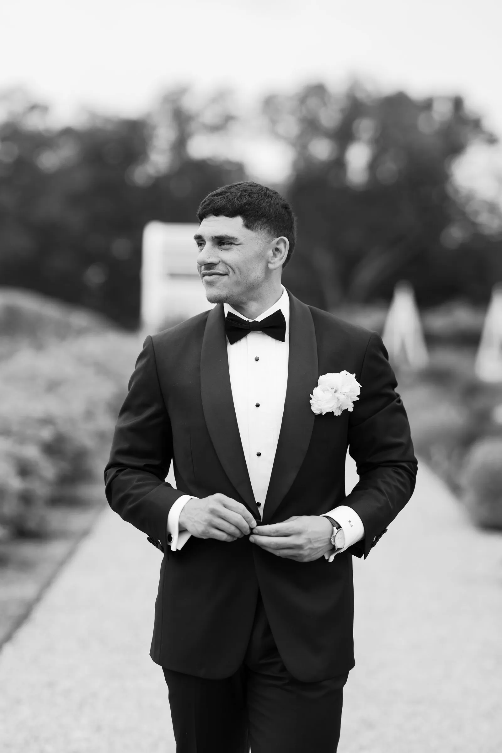 Avery buttoning his jacket on the garden path, in black and white