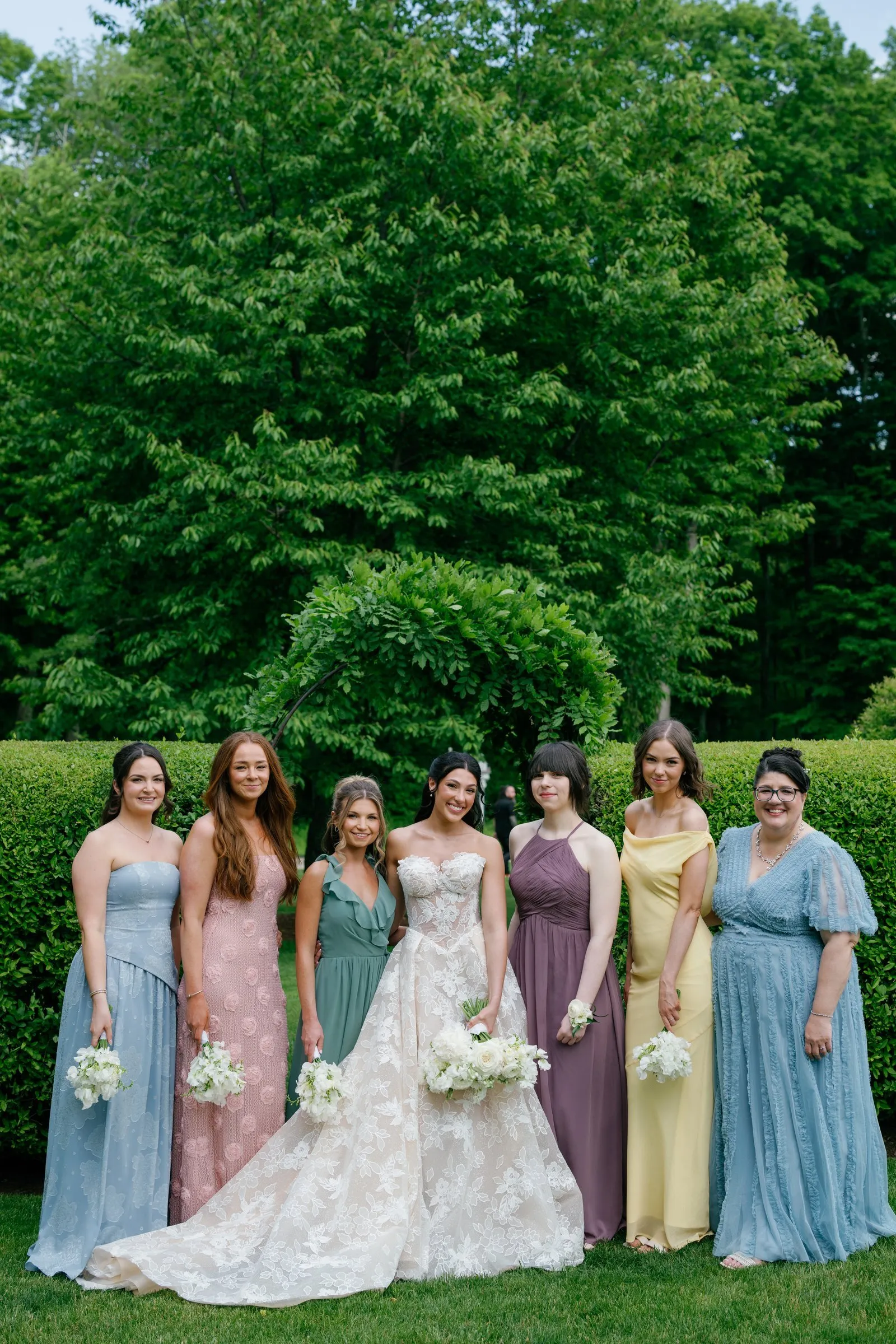 Kayla with all her bridesmaids in blue, pink, green, purple and yellow gowns
