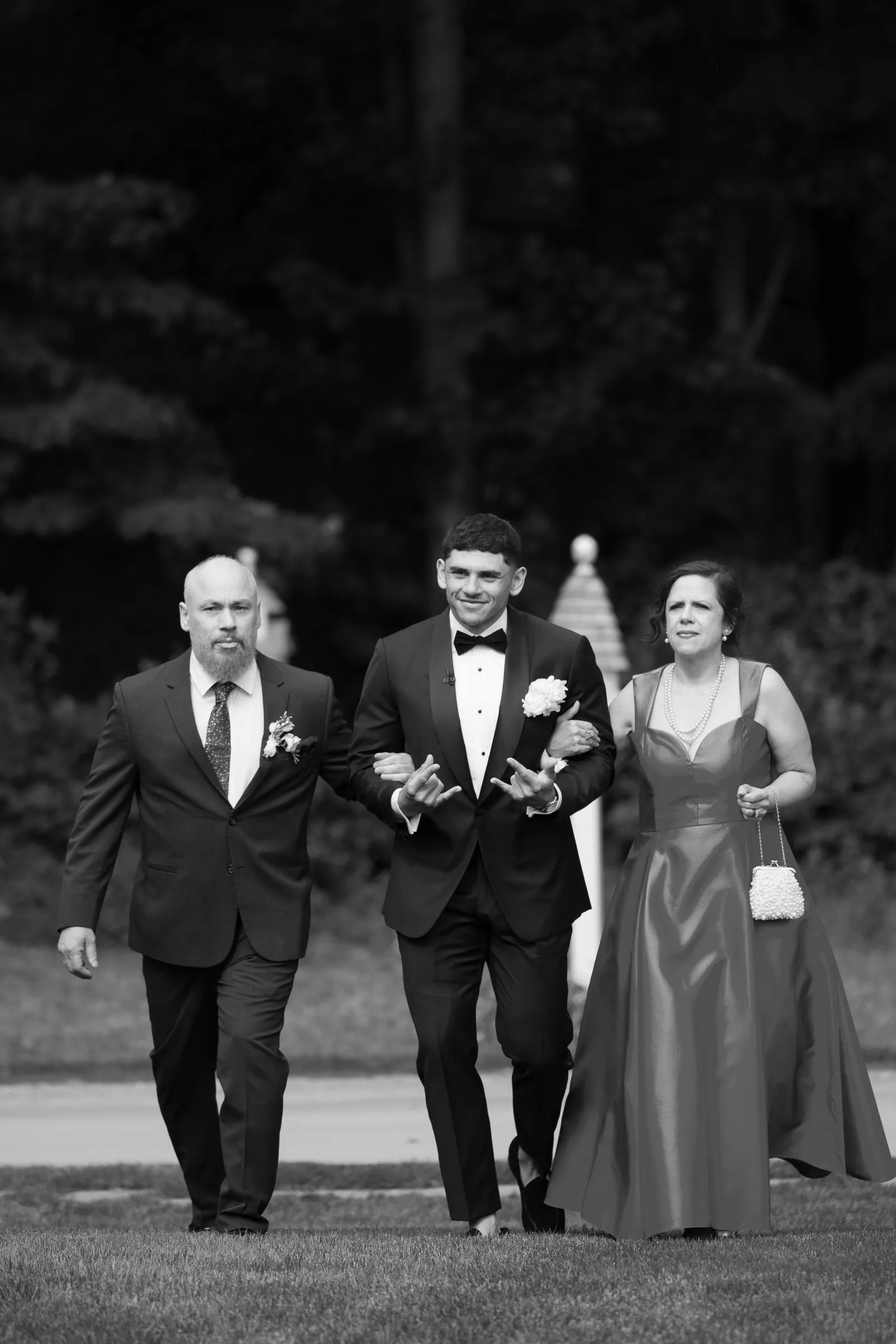 Avery walking up the aisle with his parents, in black and white