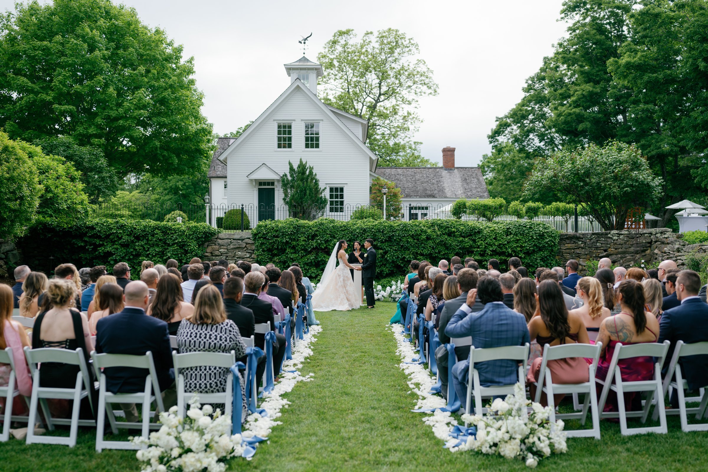 The ceremony on the lawn, guests on both sides of the aisle and the white chapel behind