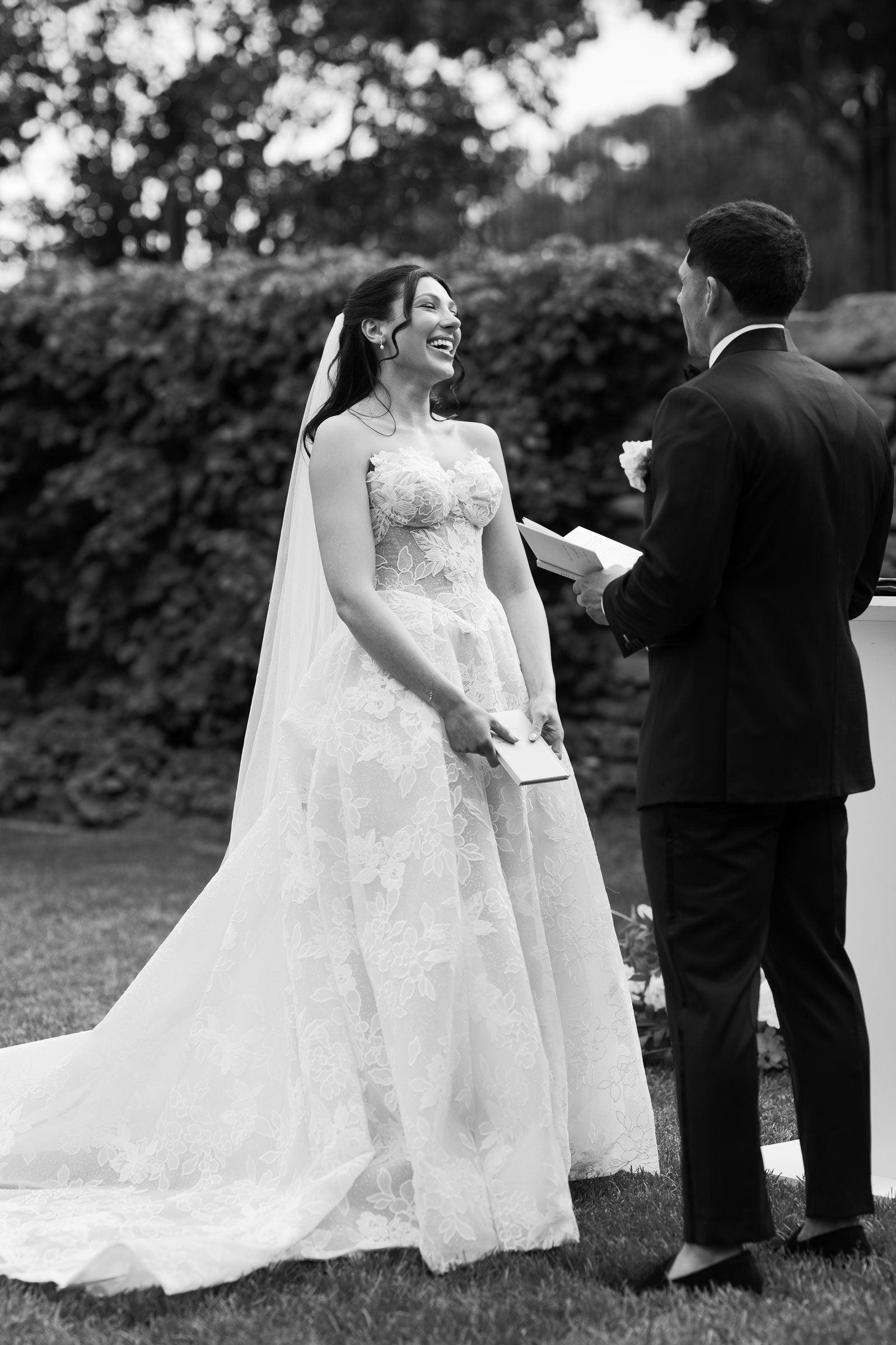 Kayla laughing as she reads her vows, in black and white