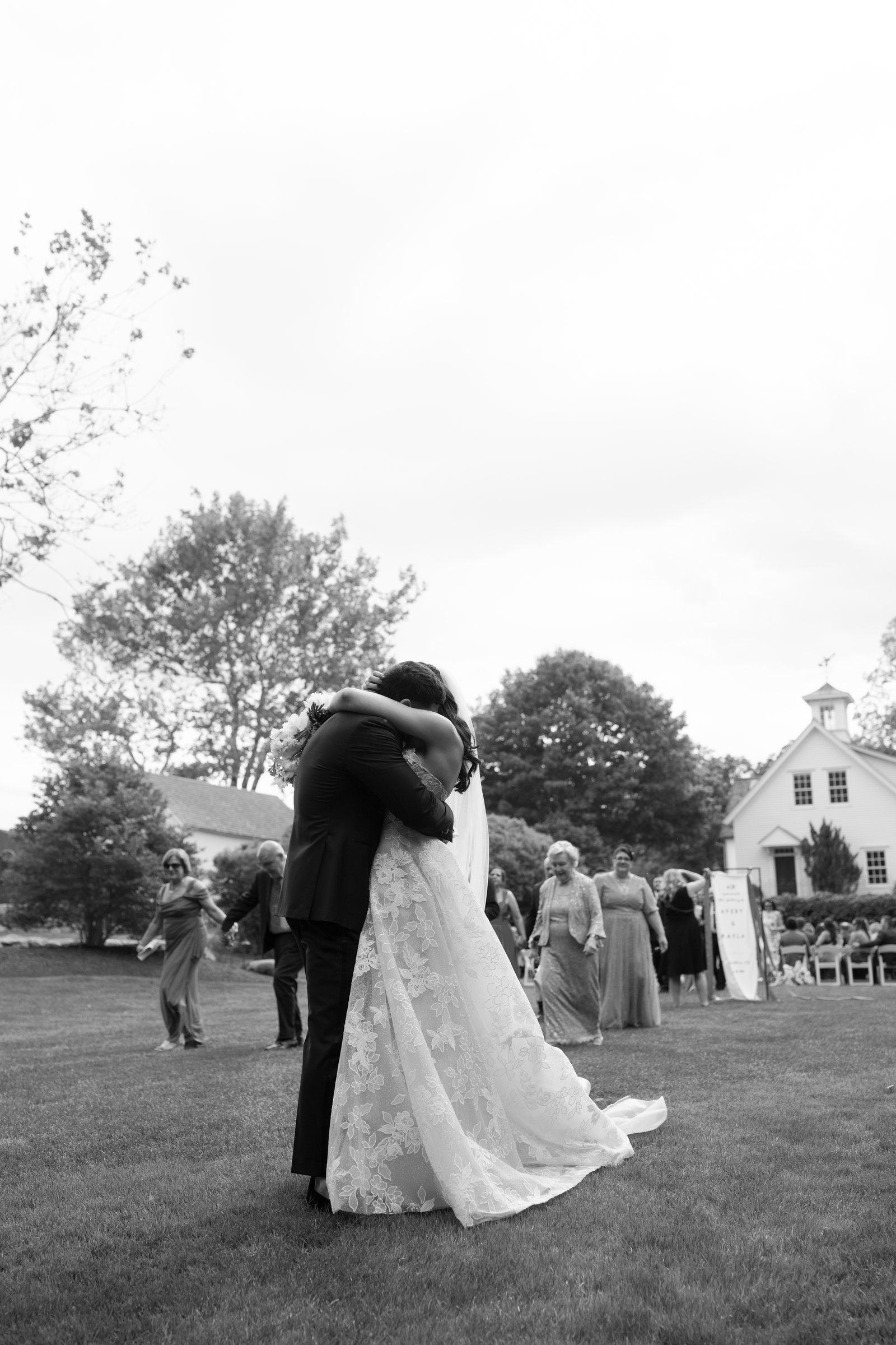 Kayla and Avery embracing on the lawn after the ceremony, in black and white