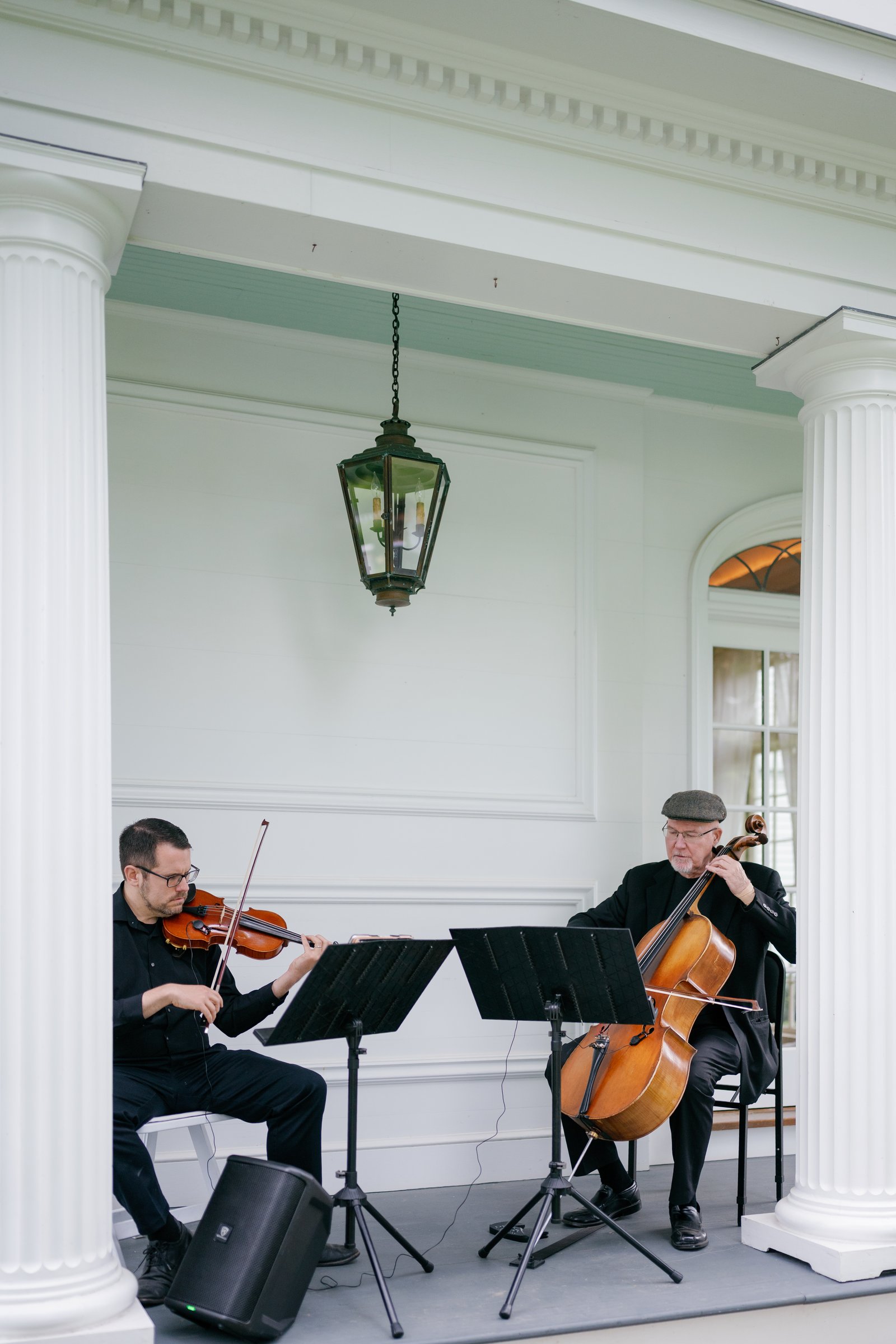 A violinist and a cellist playing on the porch at cocktail hour