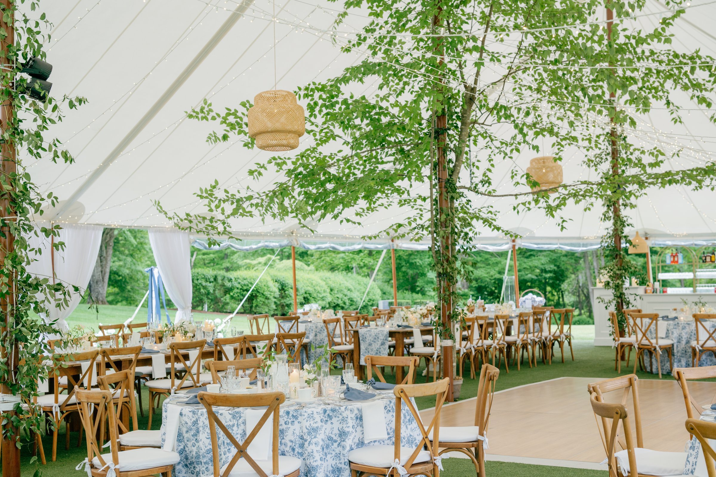 The tent set for dinner, with birch trees and rattan lanterns