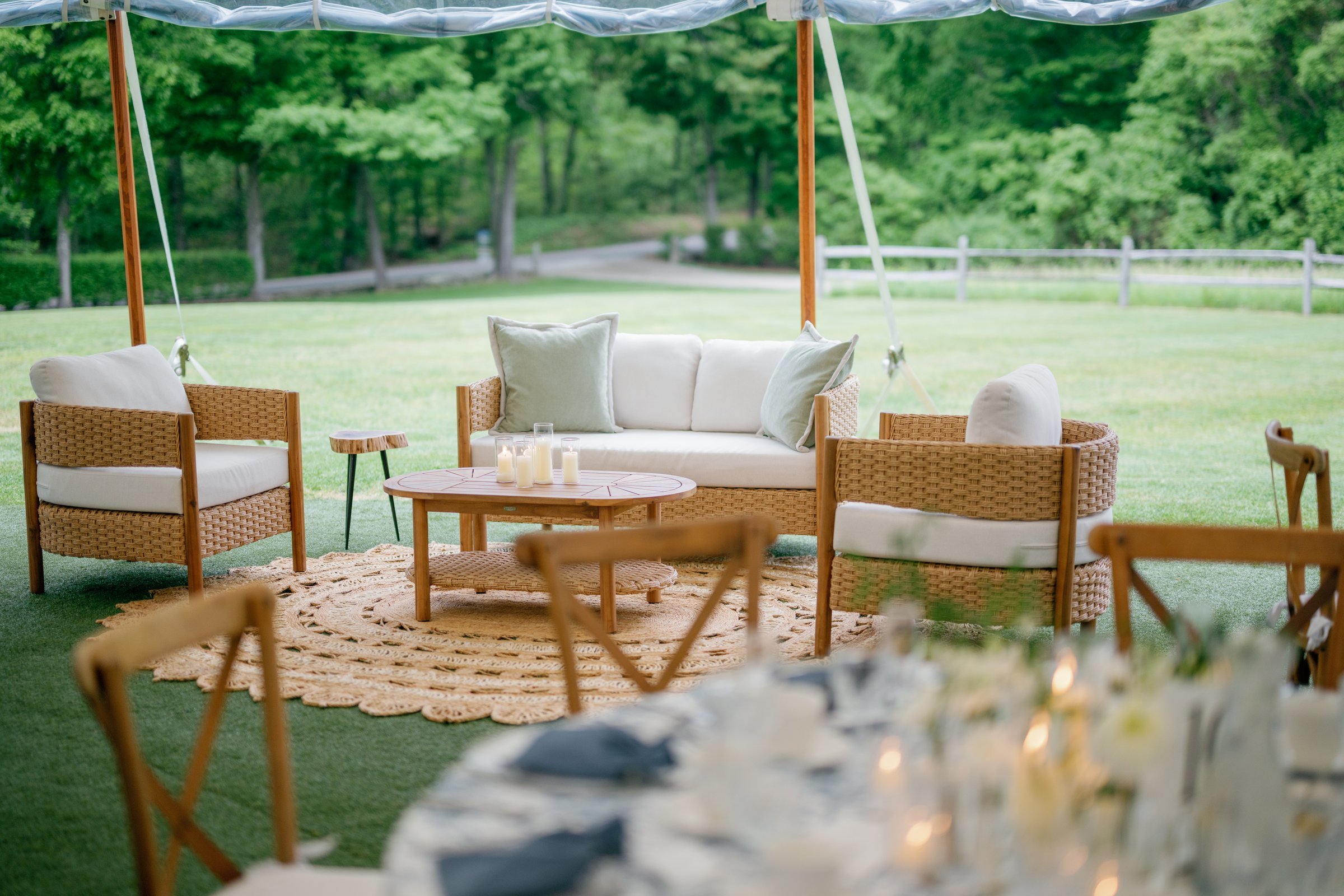 The lounge of rattan sofas on the lawn beside the tent