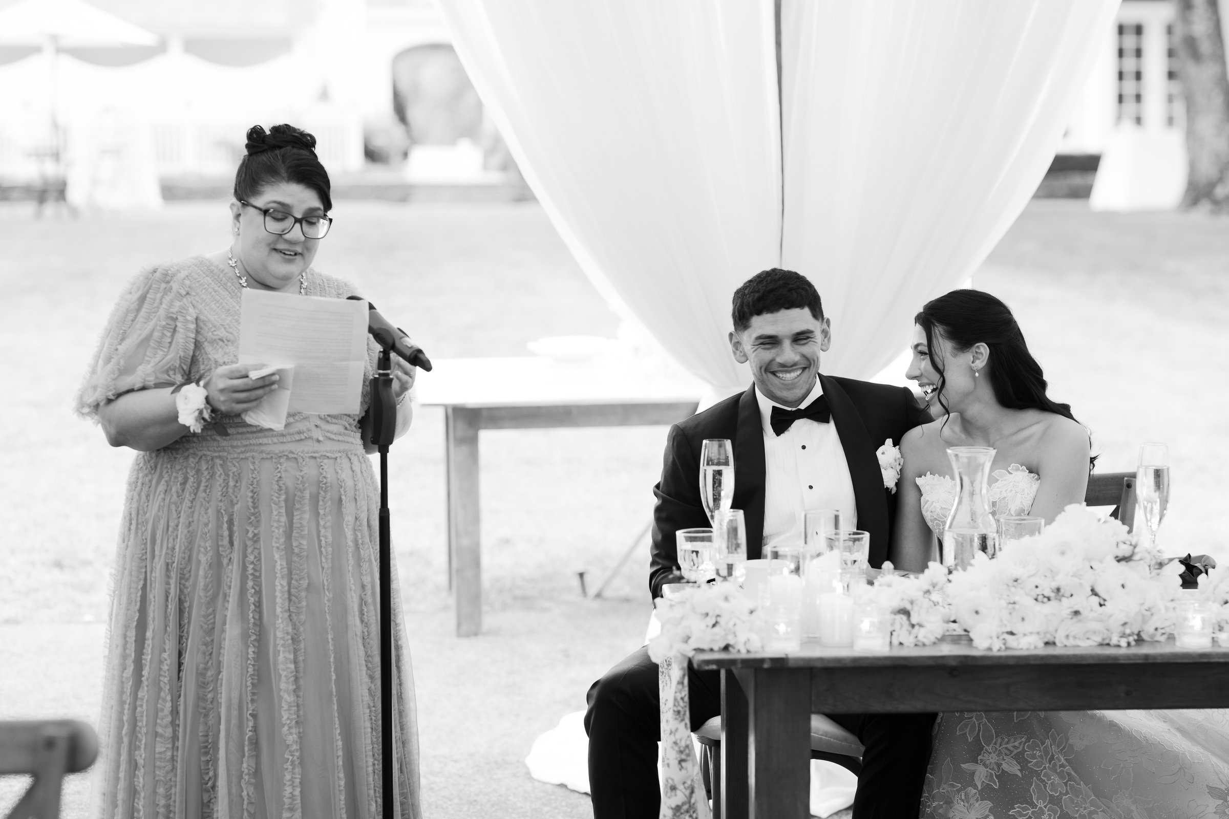 A toast for Kayla and Avery as they listen at the sweetheart table, in black and white