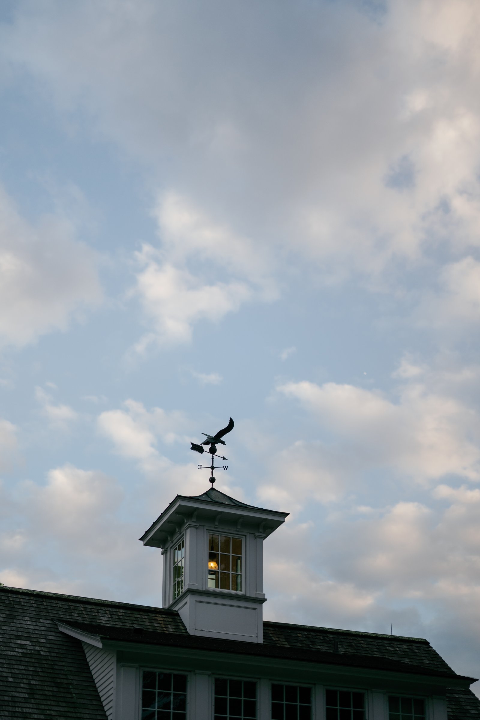 The cupola and weathervane on the barn roof against the evening sky