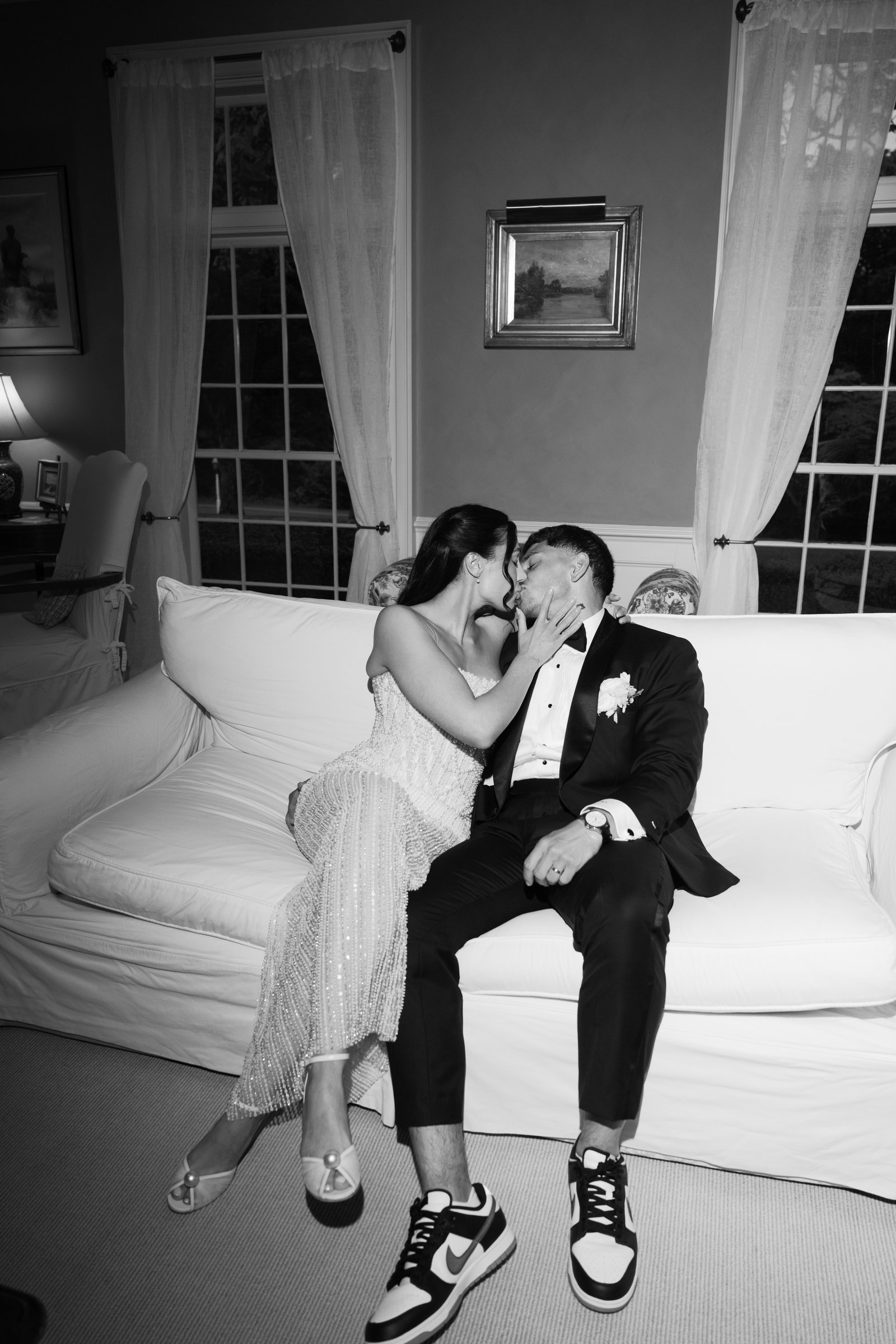 Kayla and Avery kissing on a white sofa inside the house, in black and white