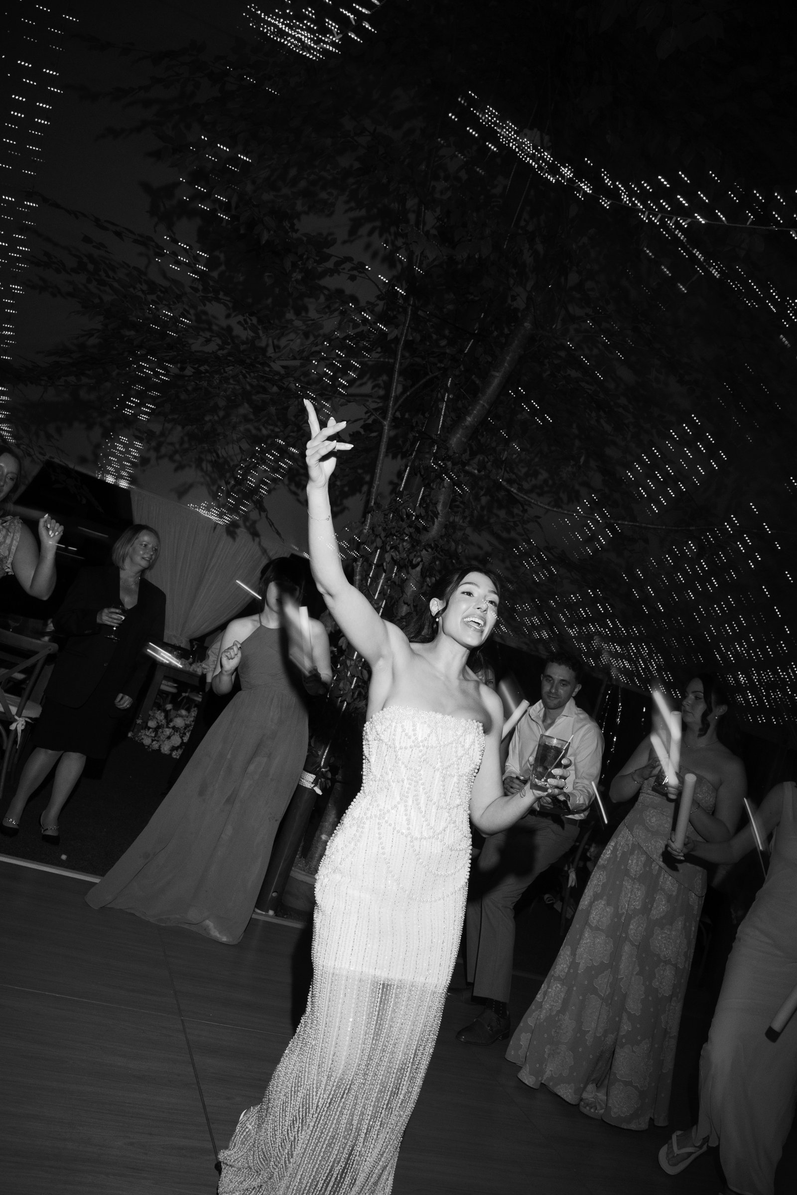 Kayla with her arm raised on the dance floor, in black and white