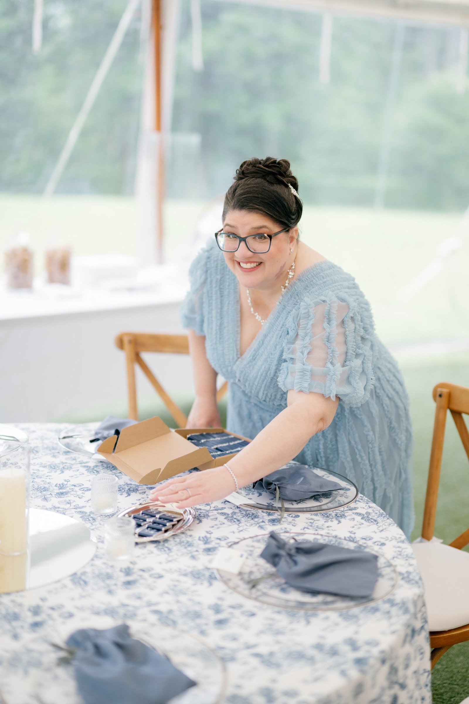 Bonnie, Kayla's mother, setting favours on a blue toile table in the tent before the guests arrive