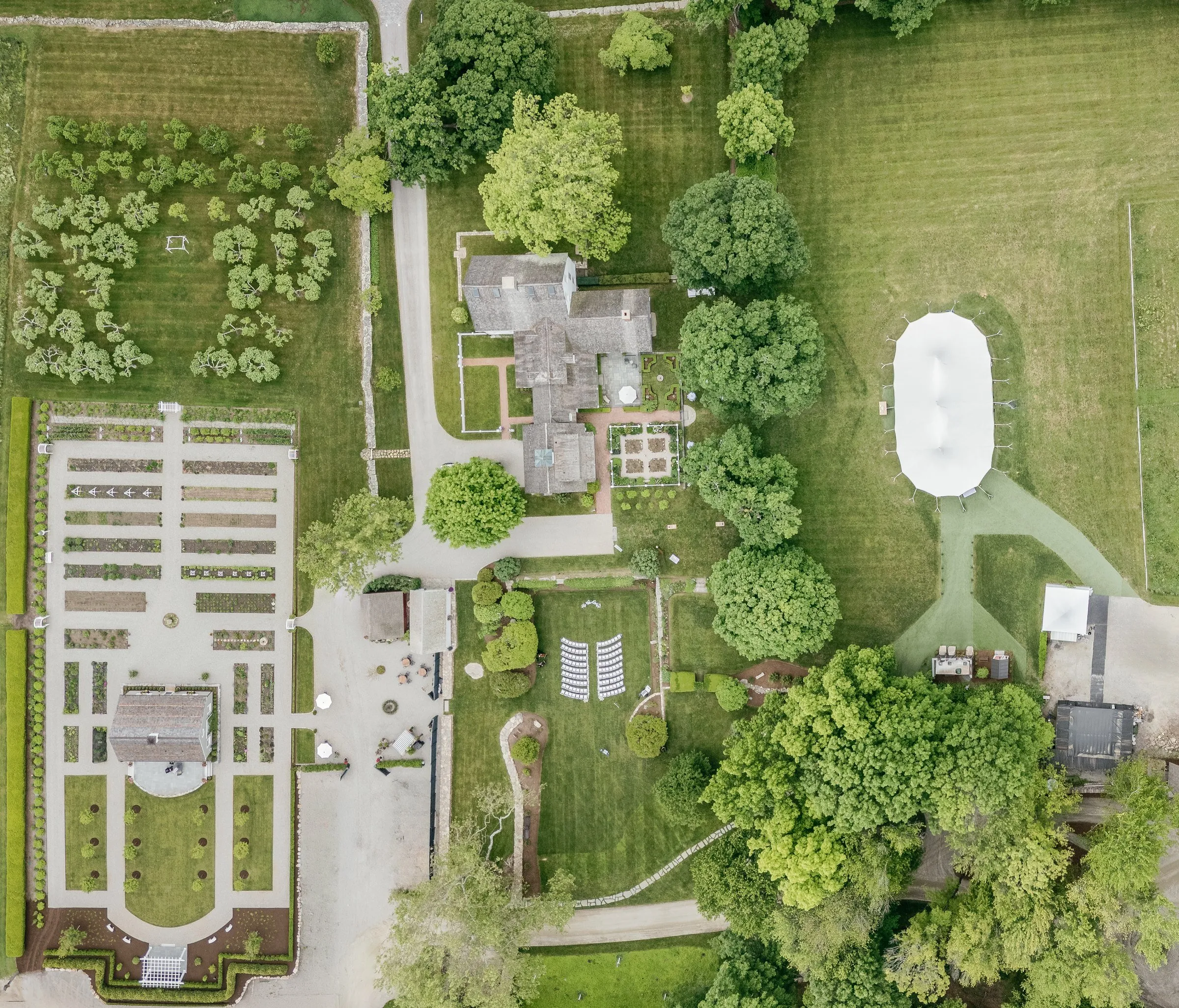 Aerial view of Smith Farm Gardens before the ceremony: the formal gardens, the farmhouse, the ceremony chairs and the white sailcloth tent in the meadow
