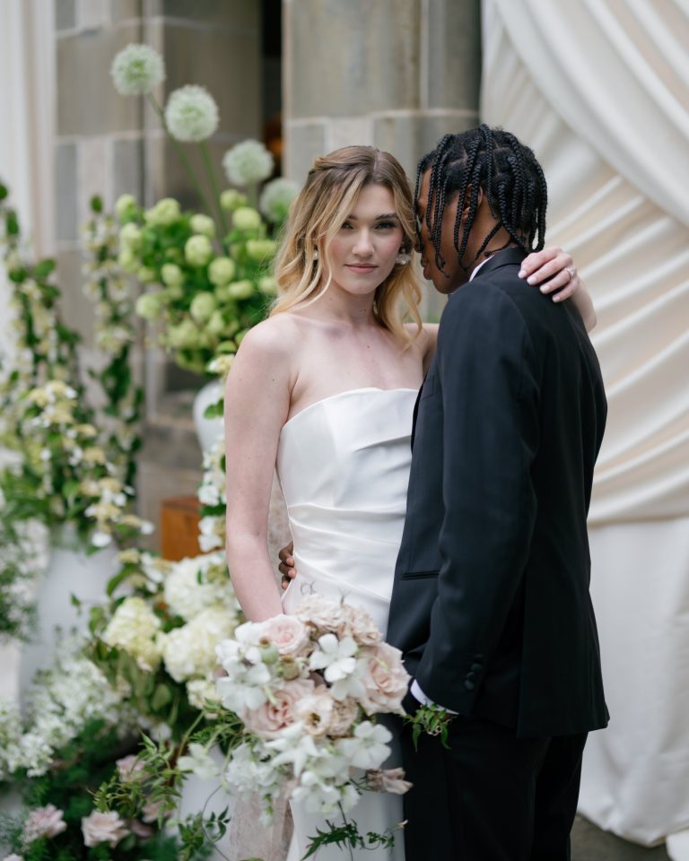 Couple in black tie beside white florals, natural light, by Shukhrat Kamalov
