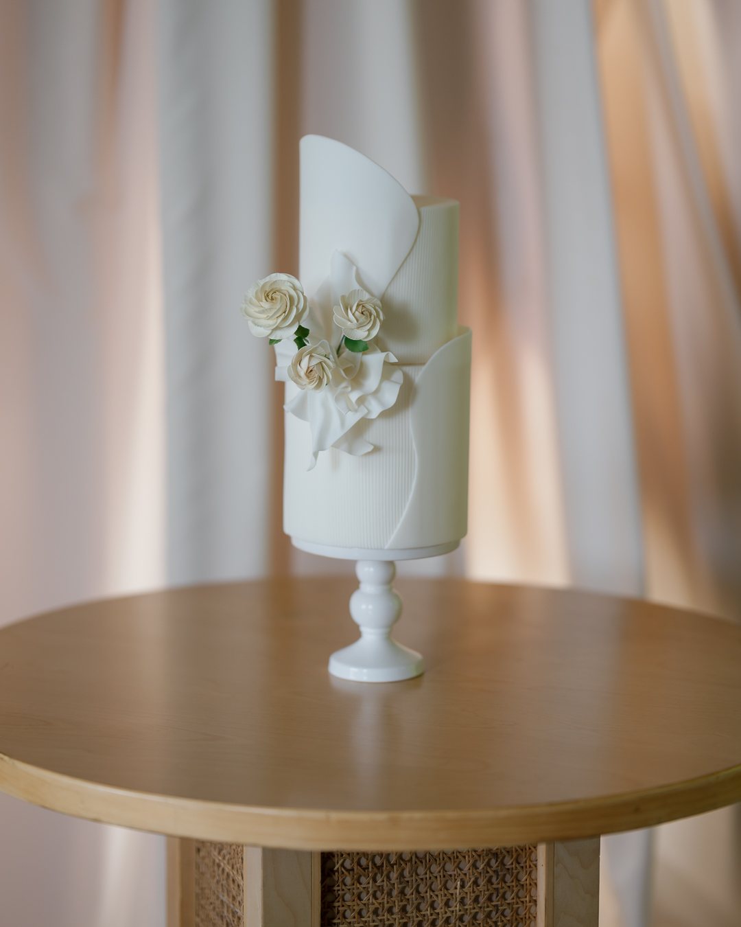 White wedding cake on a wooden table. Photographed by Shukhrat Kamalov.