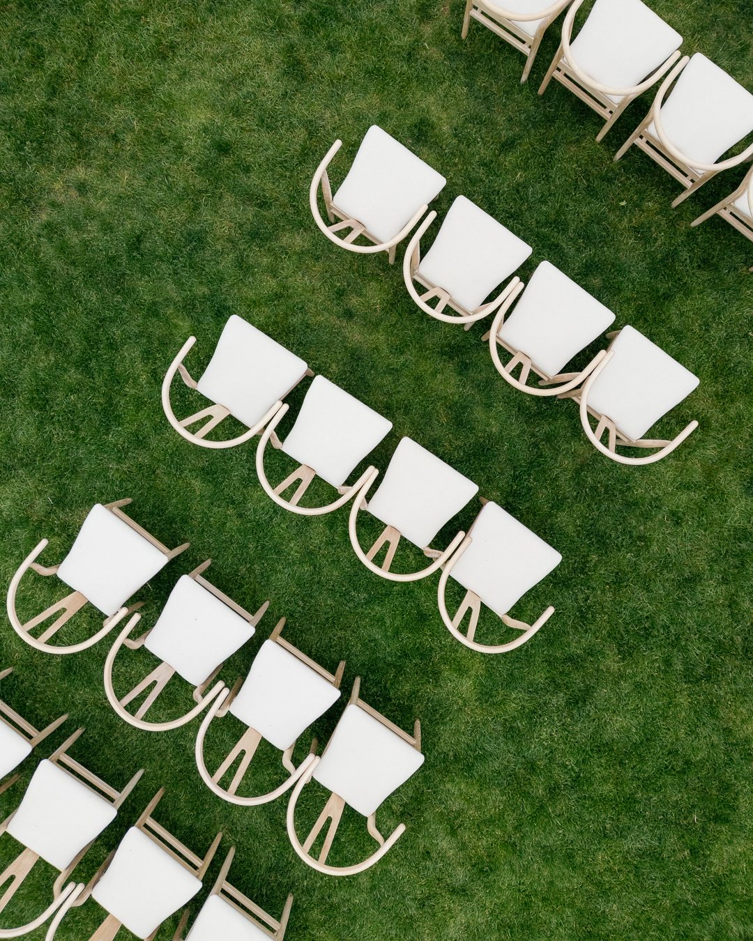 Rows of white ceremony chairs on the lawn from above. Photographed by Shukhrat Kamalov.