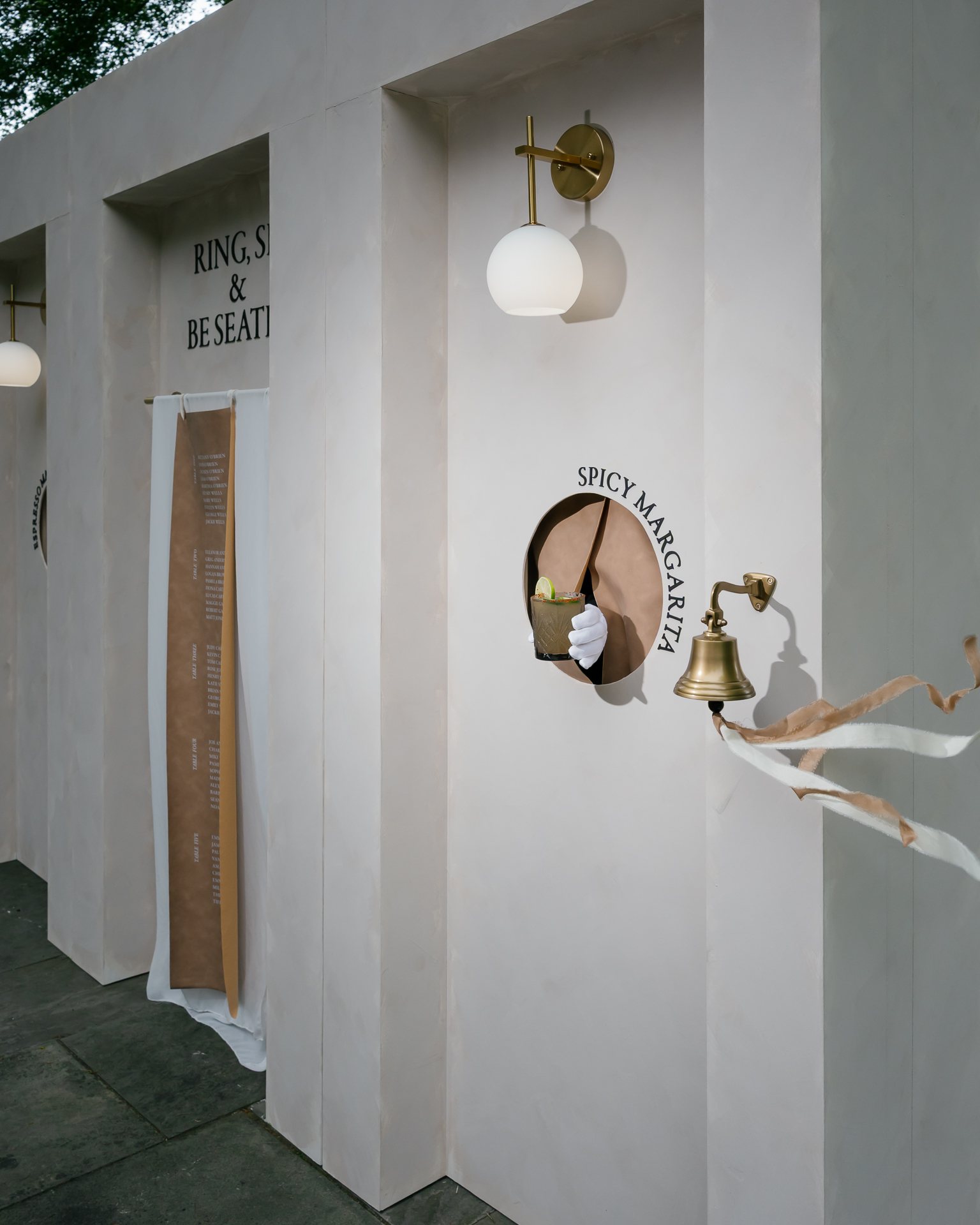 Drink wall with cocktail hatches and a Rings and Be Seated sign. Photographed by Shukhrat Kamalov.