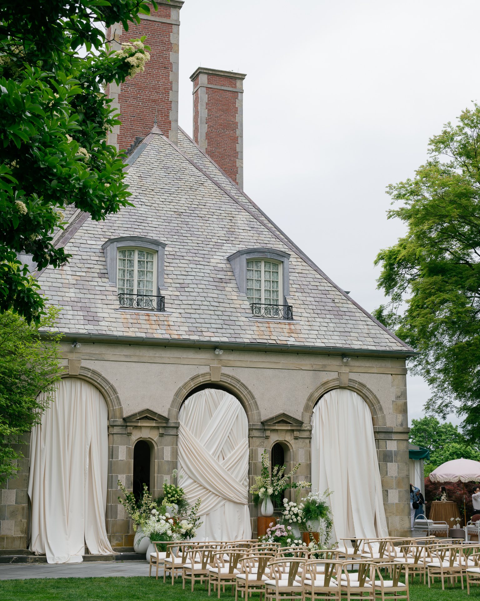 Ceremony chairs on the lawn before Glen Manor House with draped stone arches. Photographed by Shukhrat Kamalov.