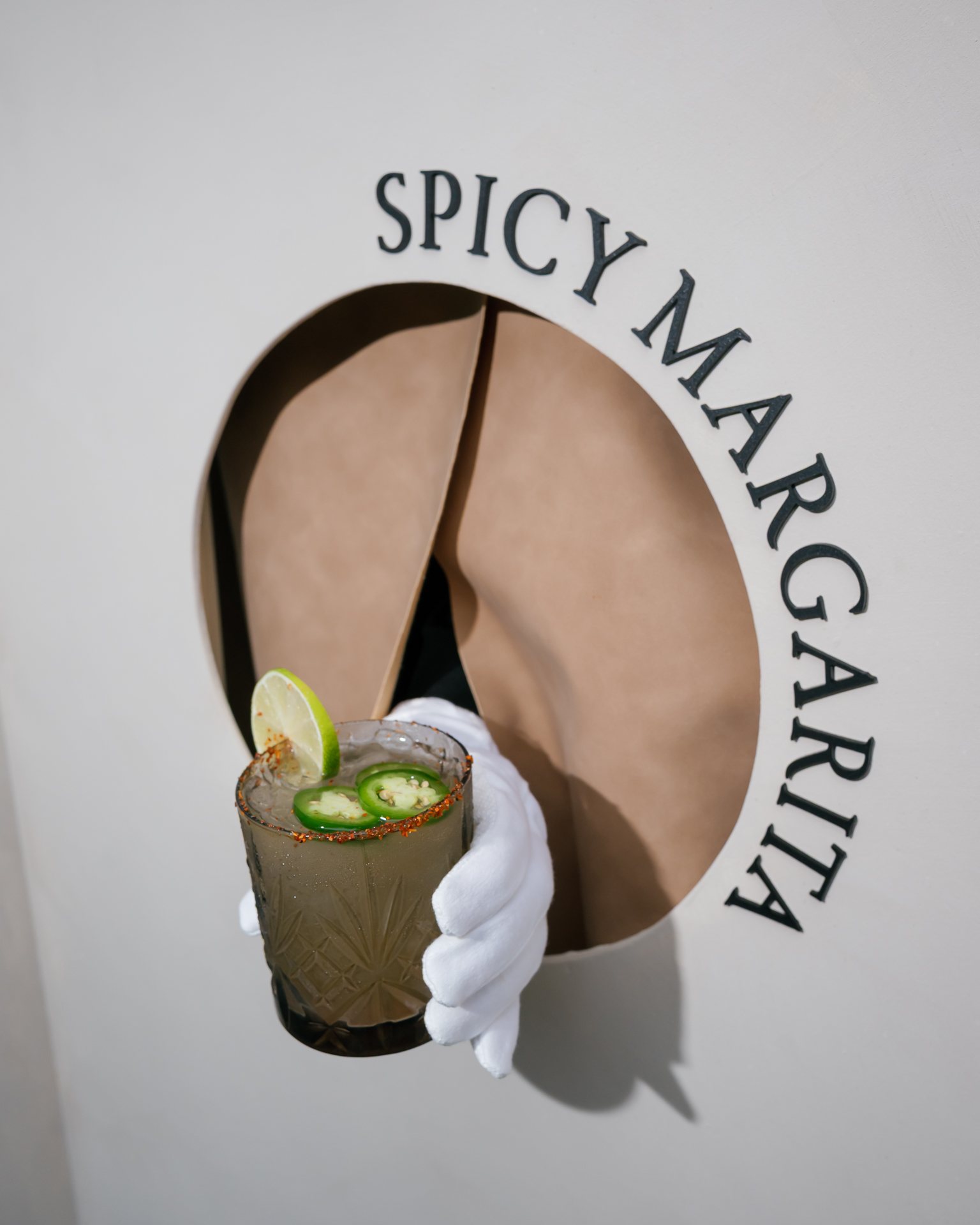 Spicy margarita served through a round hatch in a white wall. Photographed by Shukhrat Kamalov.