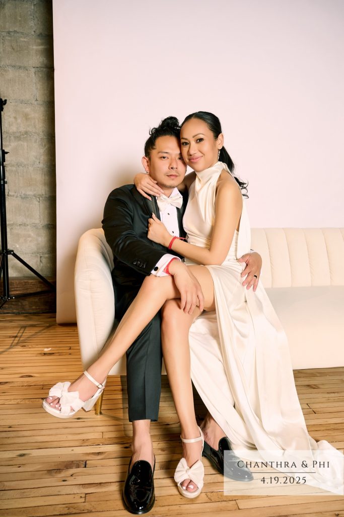 The bride and groom on the Portrait Lounge sofa, she on his lap in a white satin halter gown