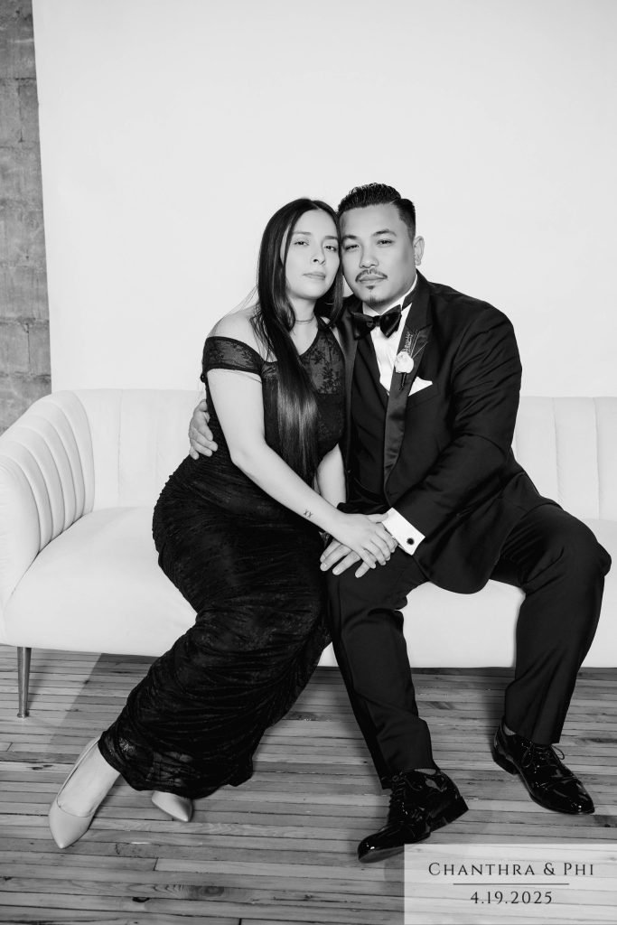 Wedding guests on the Portrait Lounge sofa in a black lace gown and tuxedo, black and white