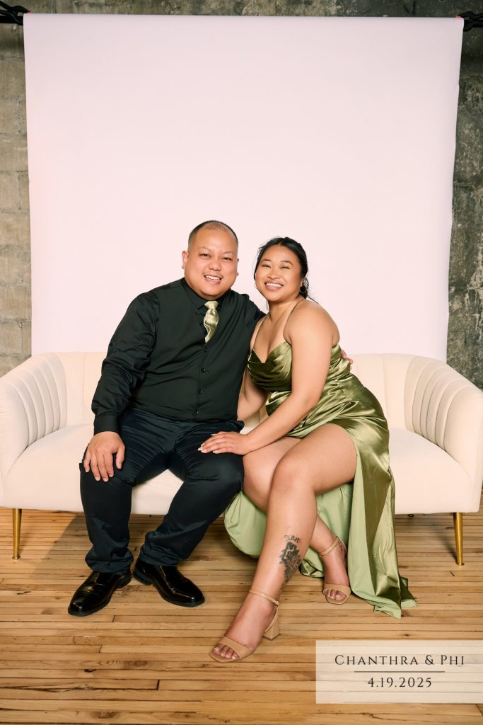 Wedding guests smiling on the Portrait Lounge sofa, she in olive satin