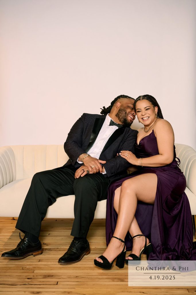 Wedding guests laughing together on the Portrait Lounge sofa, she in a plum gown