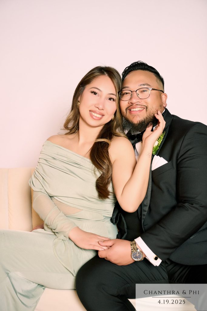 Wedding guests cheek to cheek on the Portrait Lounge sofa, she in a sage dress