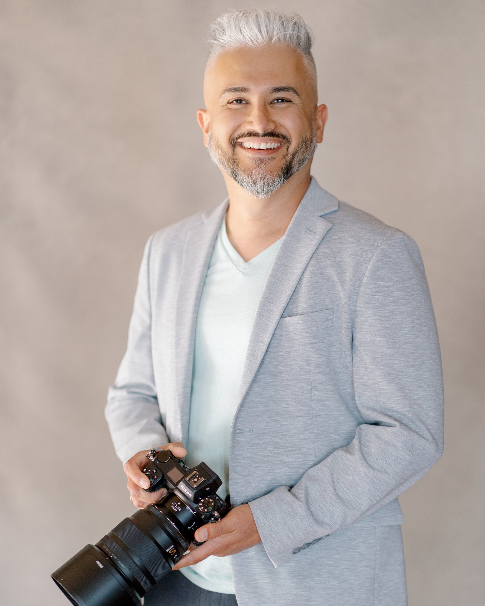 Shukhrat Kamalov, Connecticut wedding photographer, smiling at the camera with his camera in hand